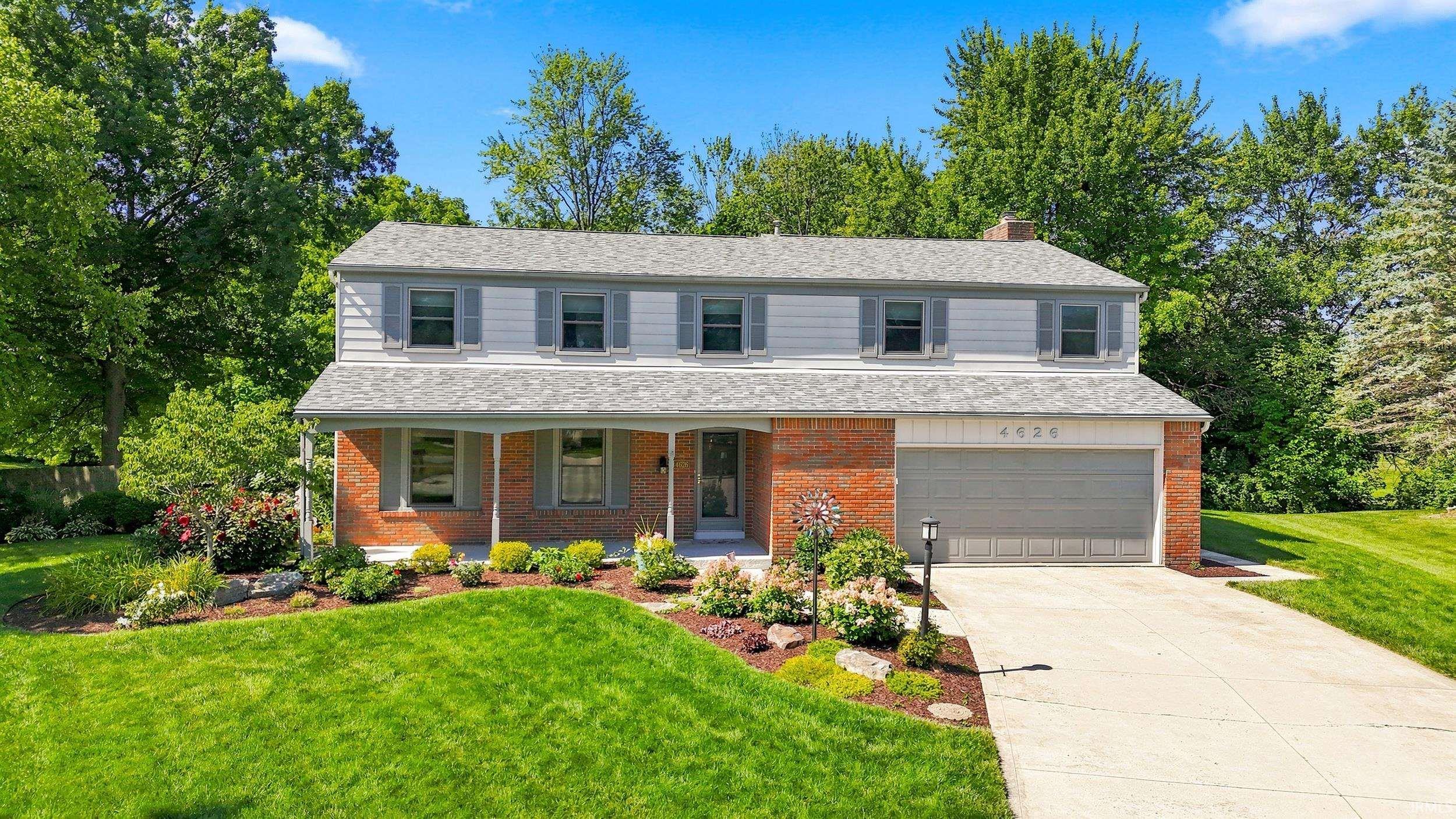 Two-story residence featuring brick and siding facade with gray shutters