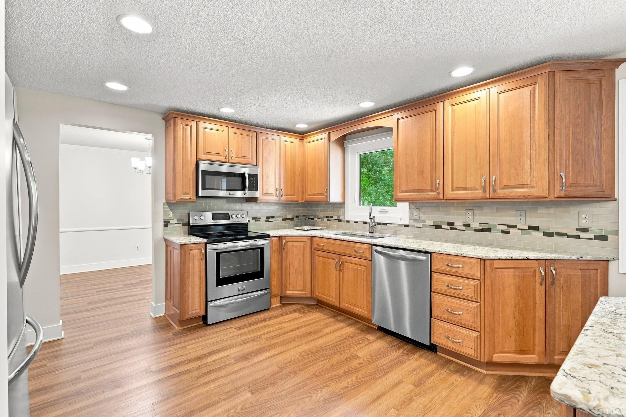 Kitchen featuring wood-finish flooring, recessed lighting, wood cabinetry, granite-finish countertops, and stainless steel appliances
