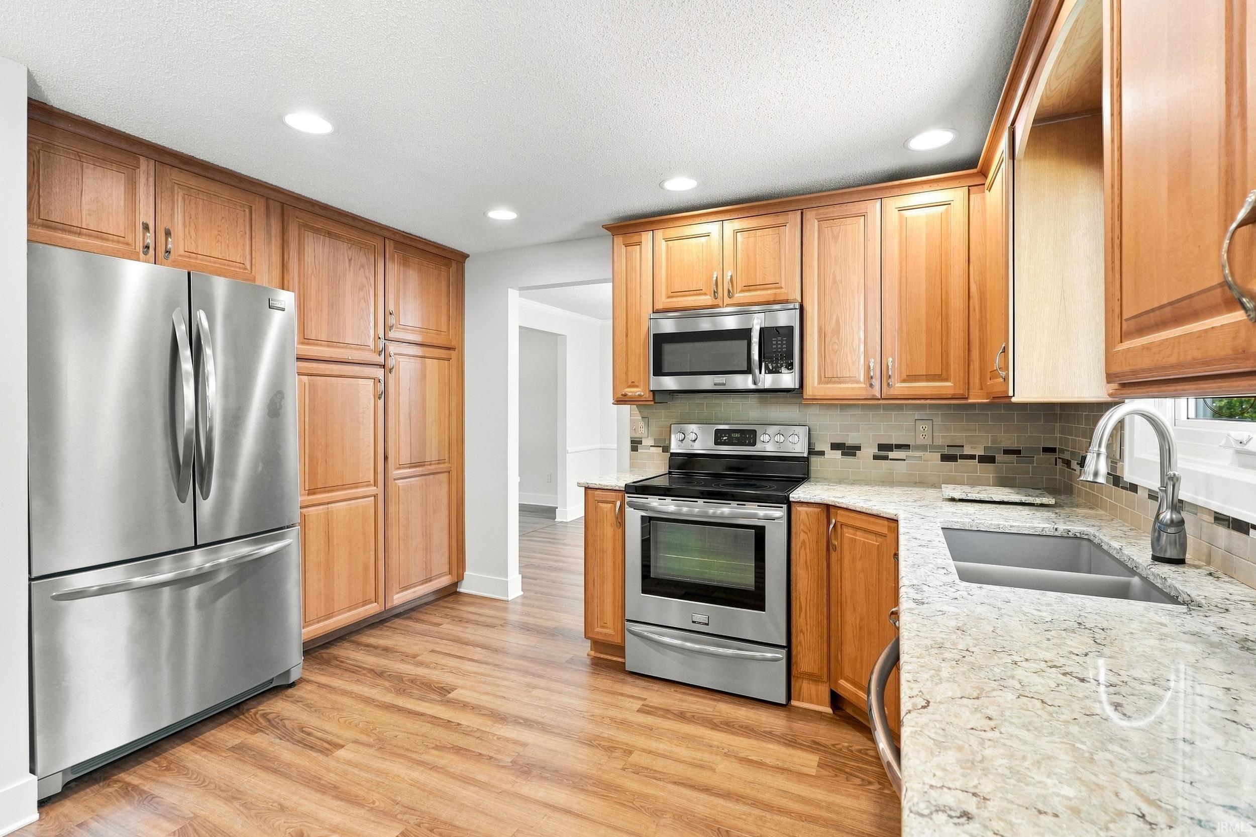 Spacious kitchen featuring warm wood cabinetry, stainless steel French-door refrigerator, and built-in microwave