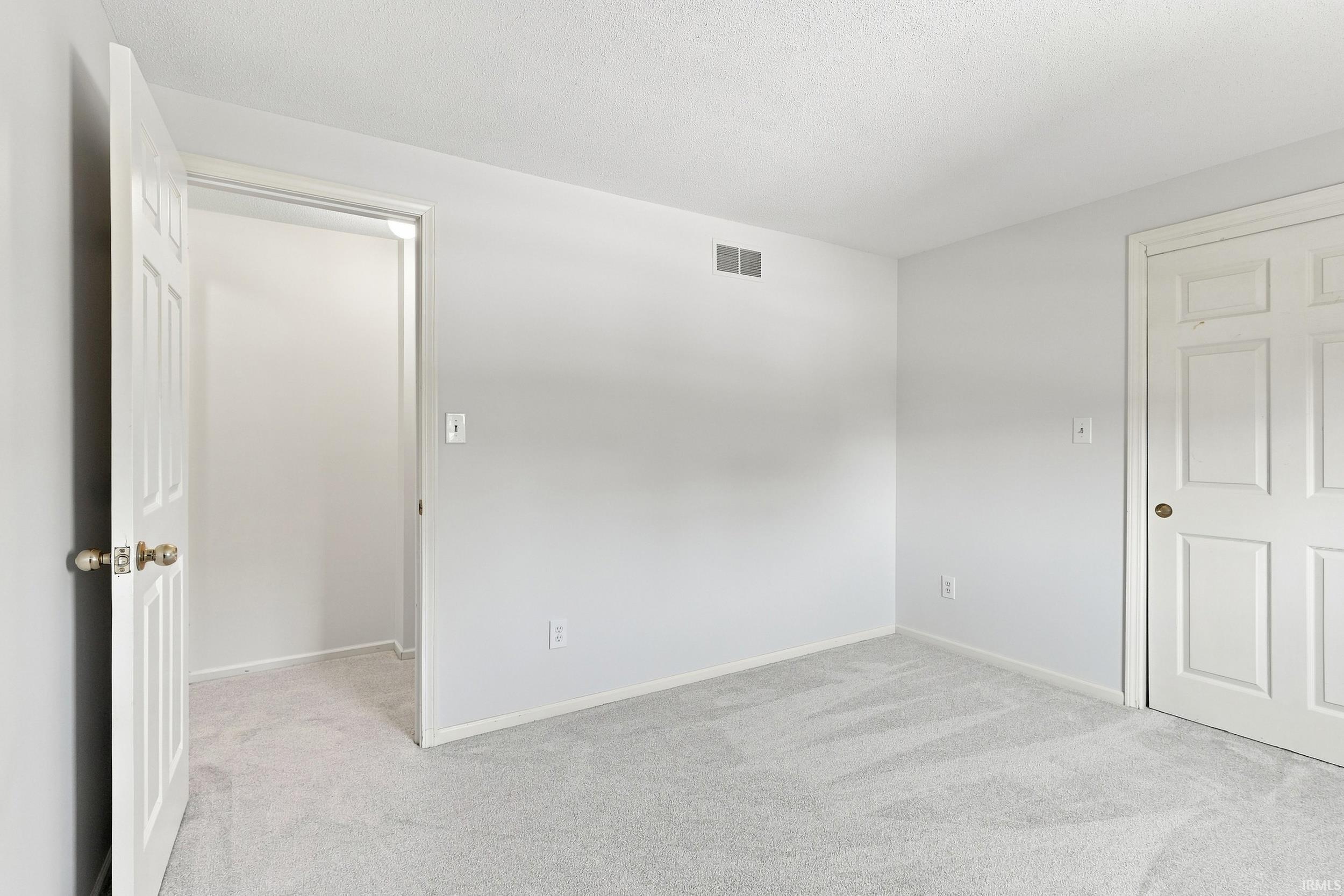 Neutral-toned room featuring light gray walls, plush gray carpeting, and white trim