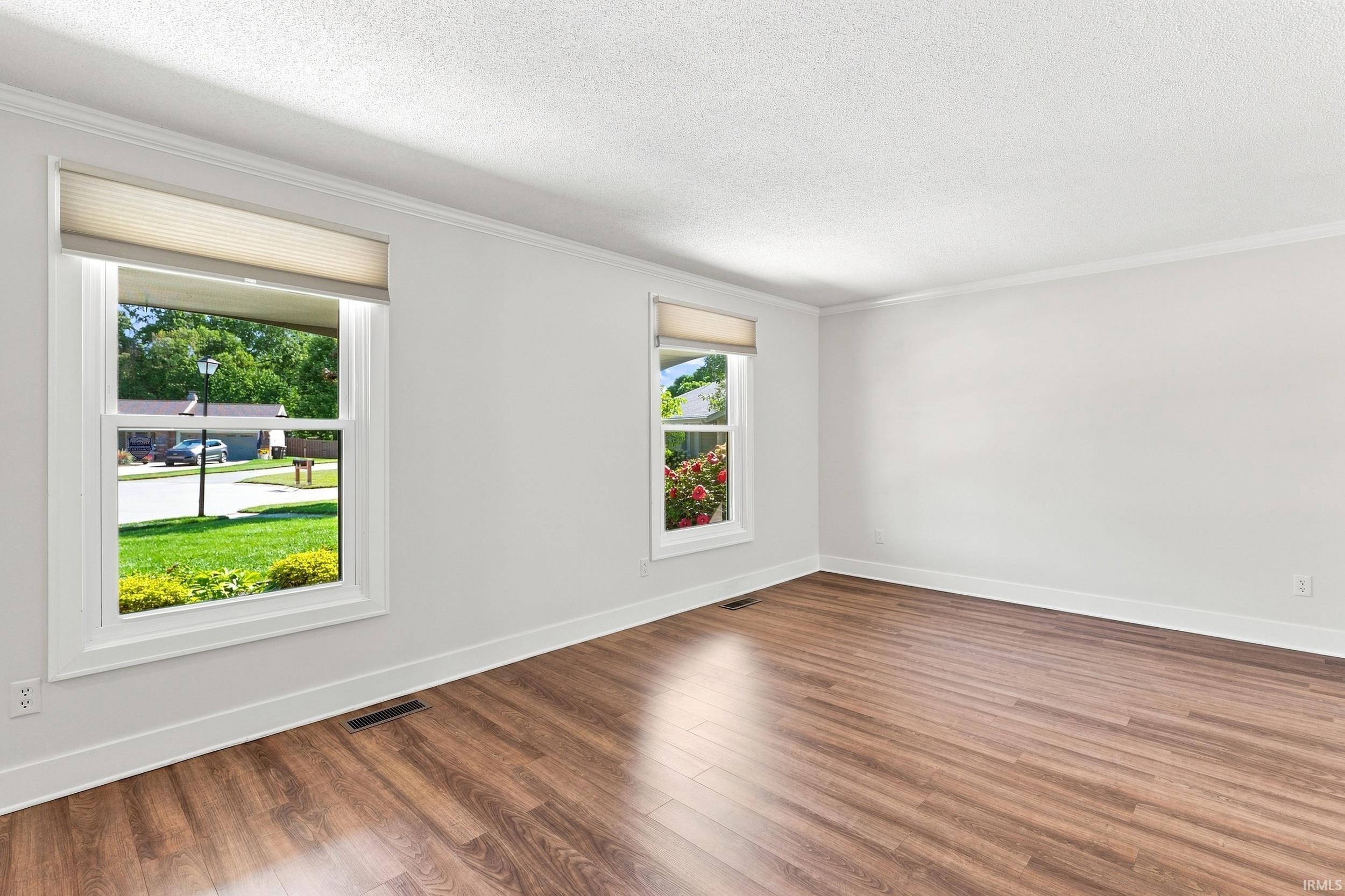 Bright and spacious room flooded with natural light through dual windows framing manicured landscaping and mature trees