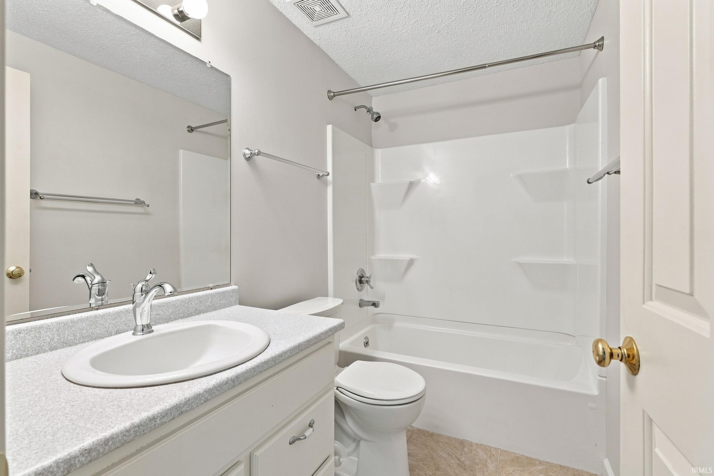 Bathroom featuring a white vanity with an integrated sink, a speckled countertop, and a chrome faucet
