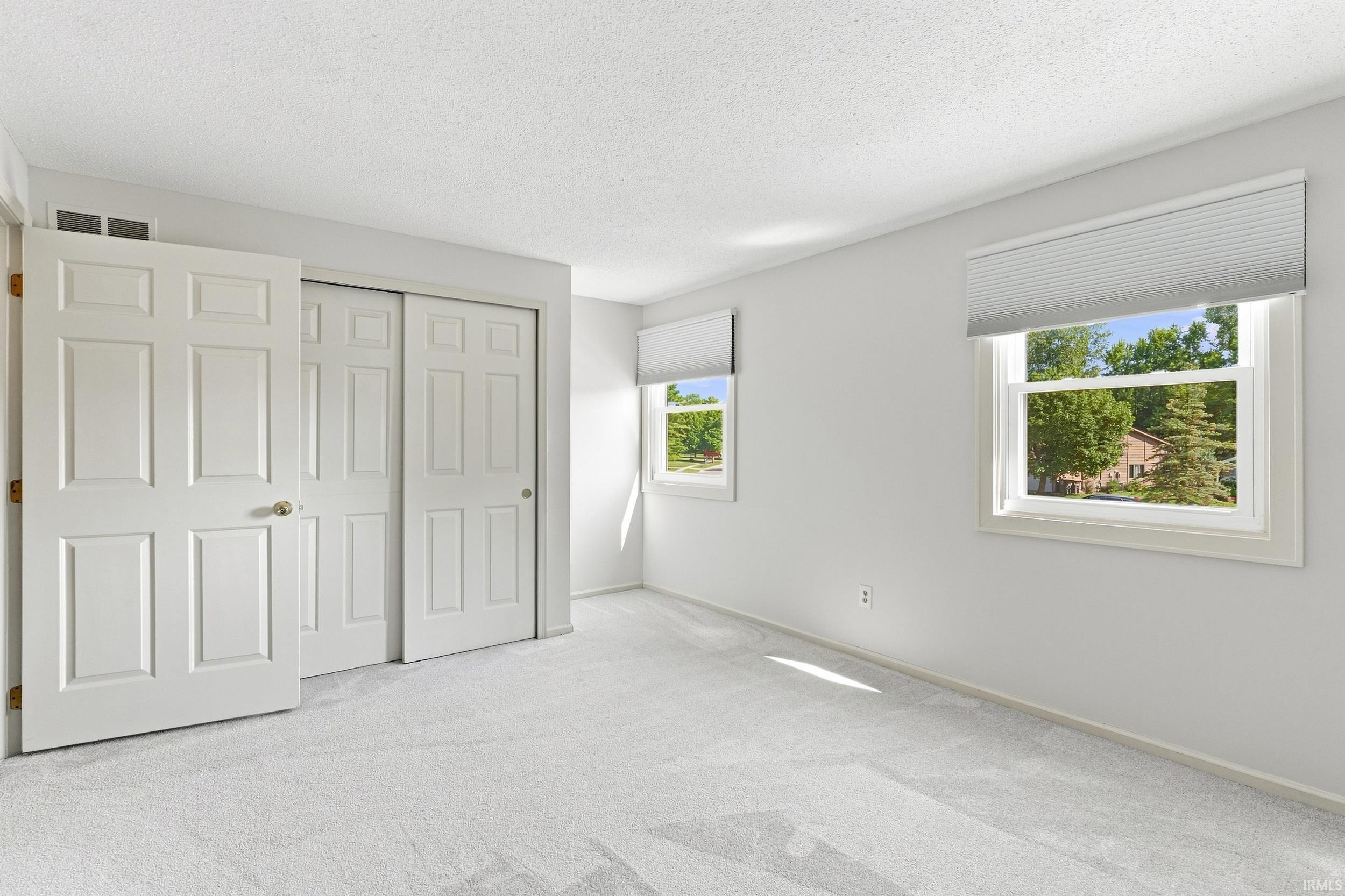 Bright room featuring two windows with horizontal blinds, providing natural light
