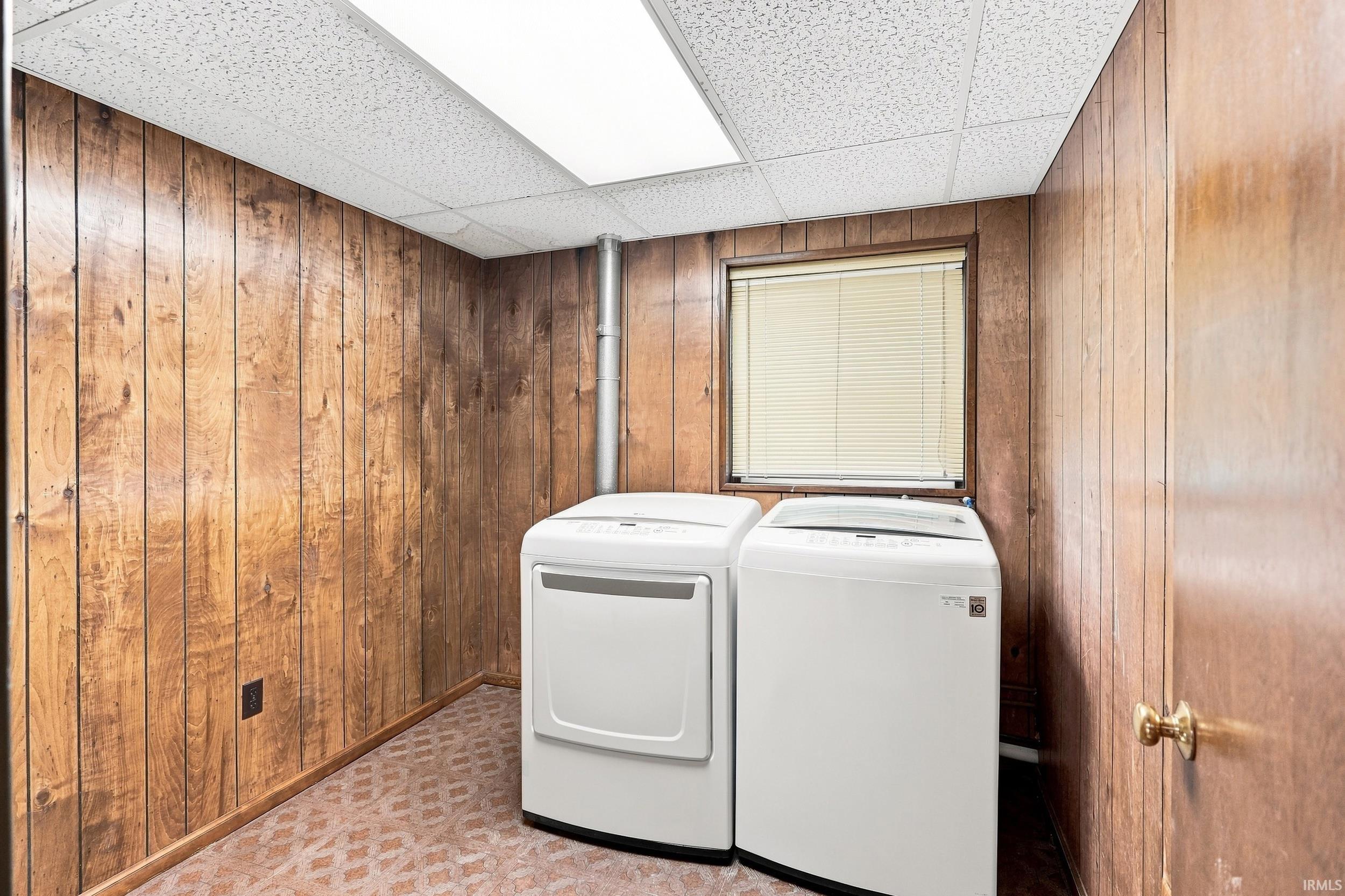 Utility area featuring wood-finish paneling, a drop ceiling with recessed lighting, and a window with blinds