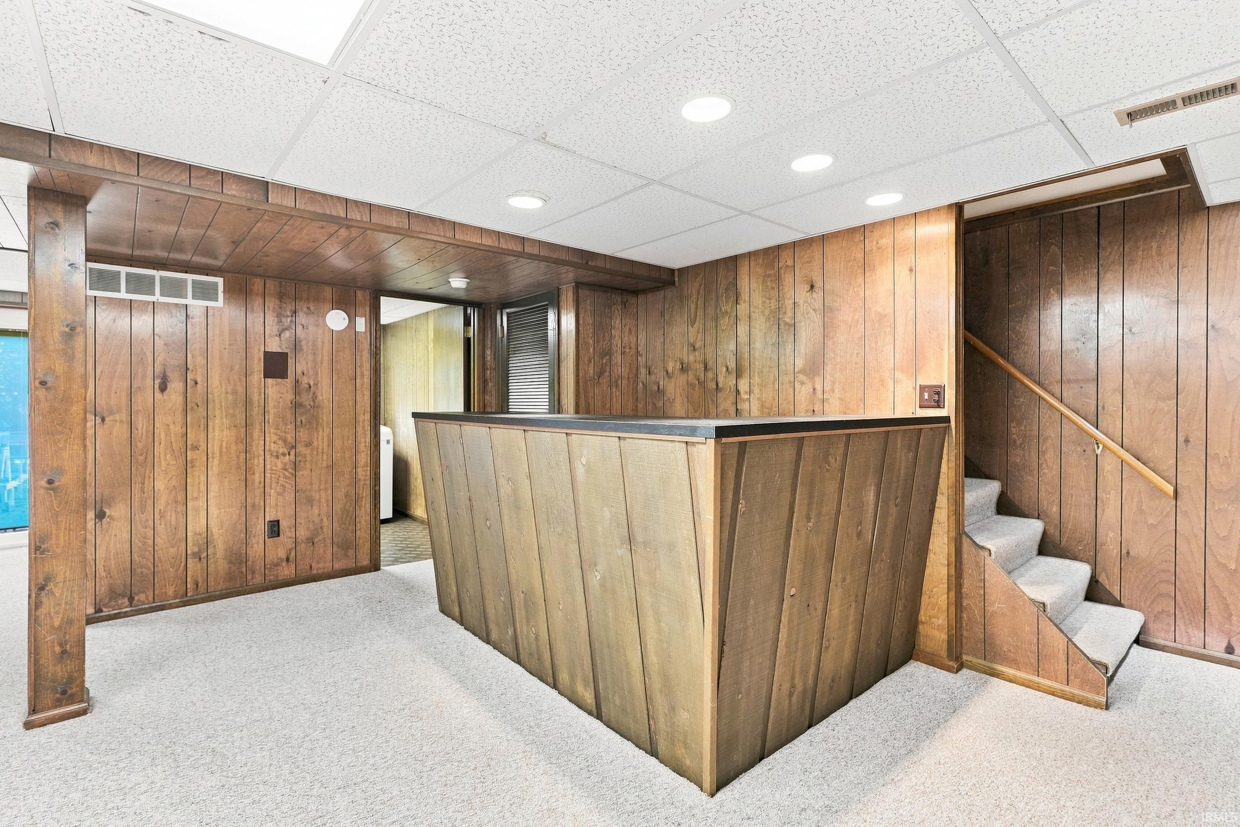 Distinctive commercial or basement space featuring rich wood-paneled walls and custom wood-finished reception desk with integrated countertop