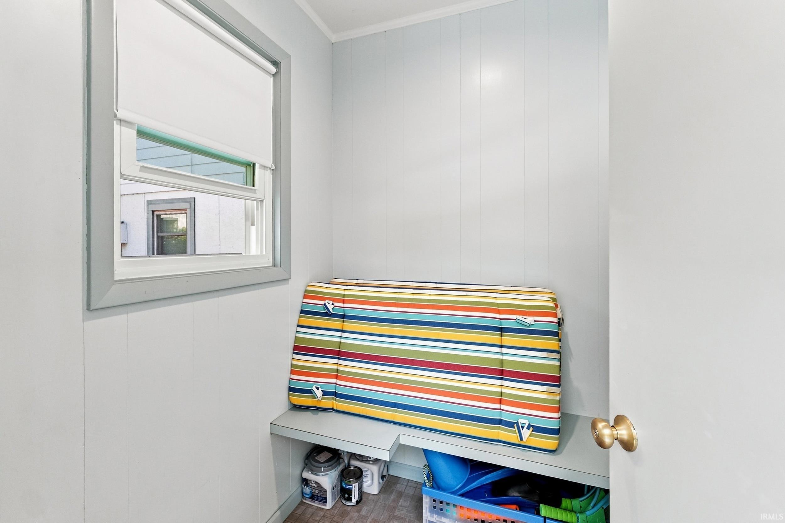 Utility room featuring bright white walls, a multi-pane window with integrated blinds, and built-in storage solutions