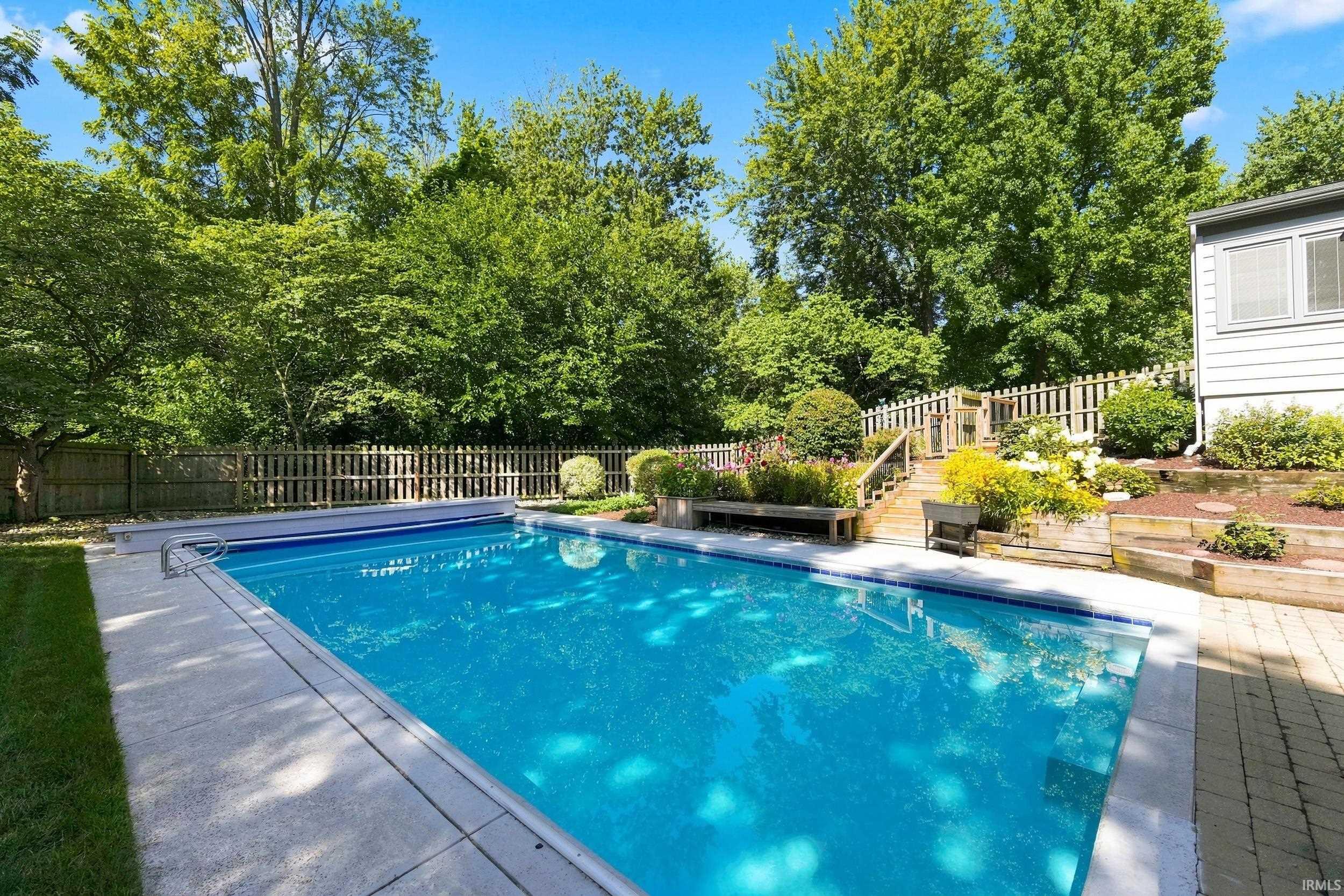 Rectangular in-ground swimming pool with a concrete surround, complemented by a paver patio