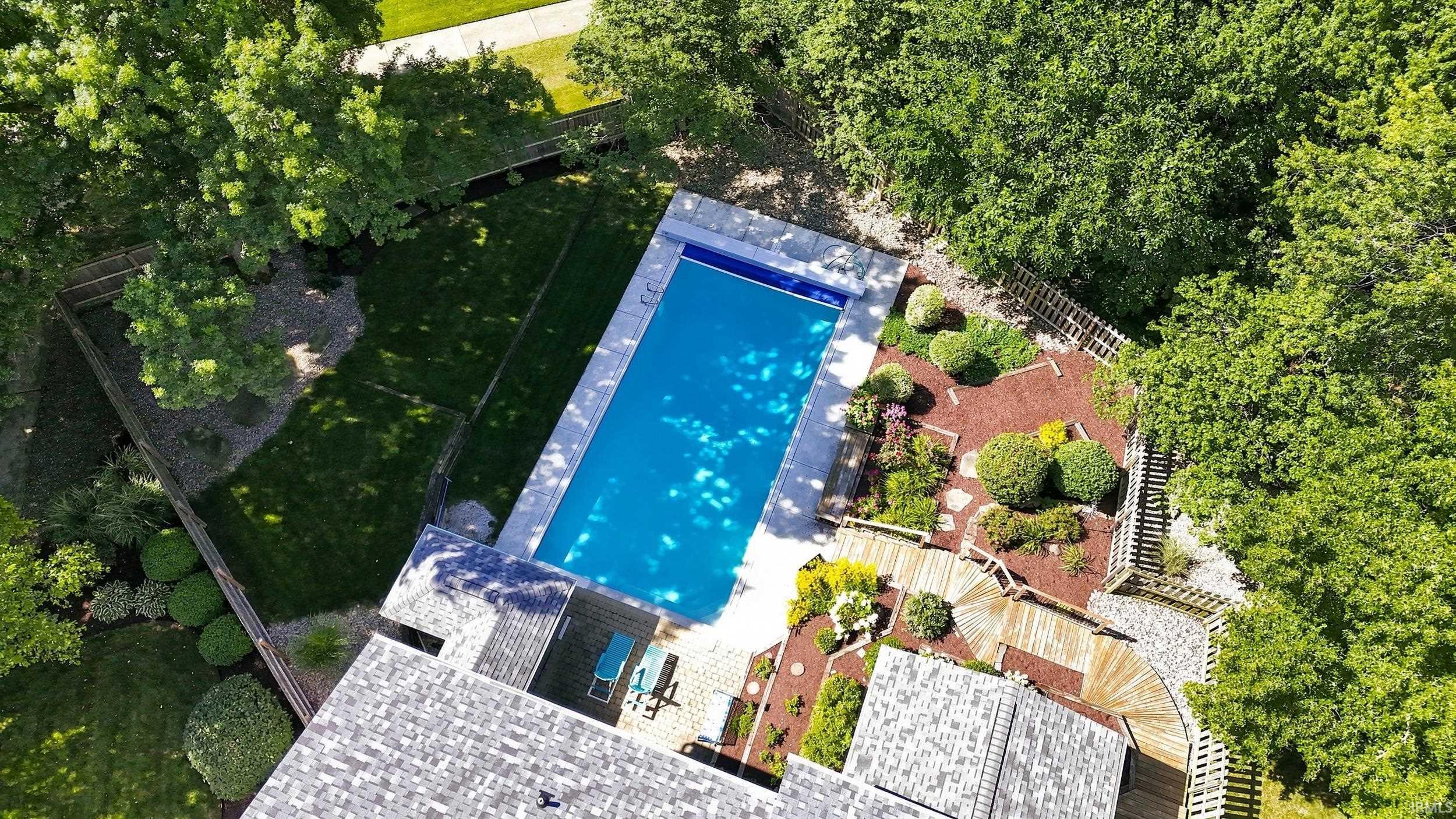 Resort-Style Swimming Pool with Heated Water Feature and Surrounding Hardscape Patio  This aerial view showcases a sparkling rectangular swimming pool as the centerpiece of an expertly designed outdoor entertainment space