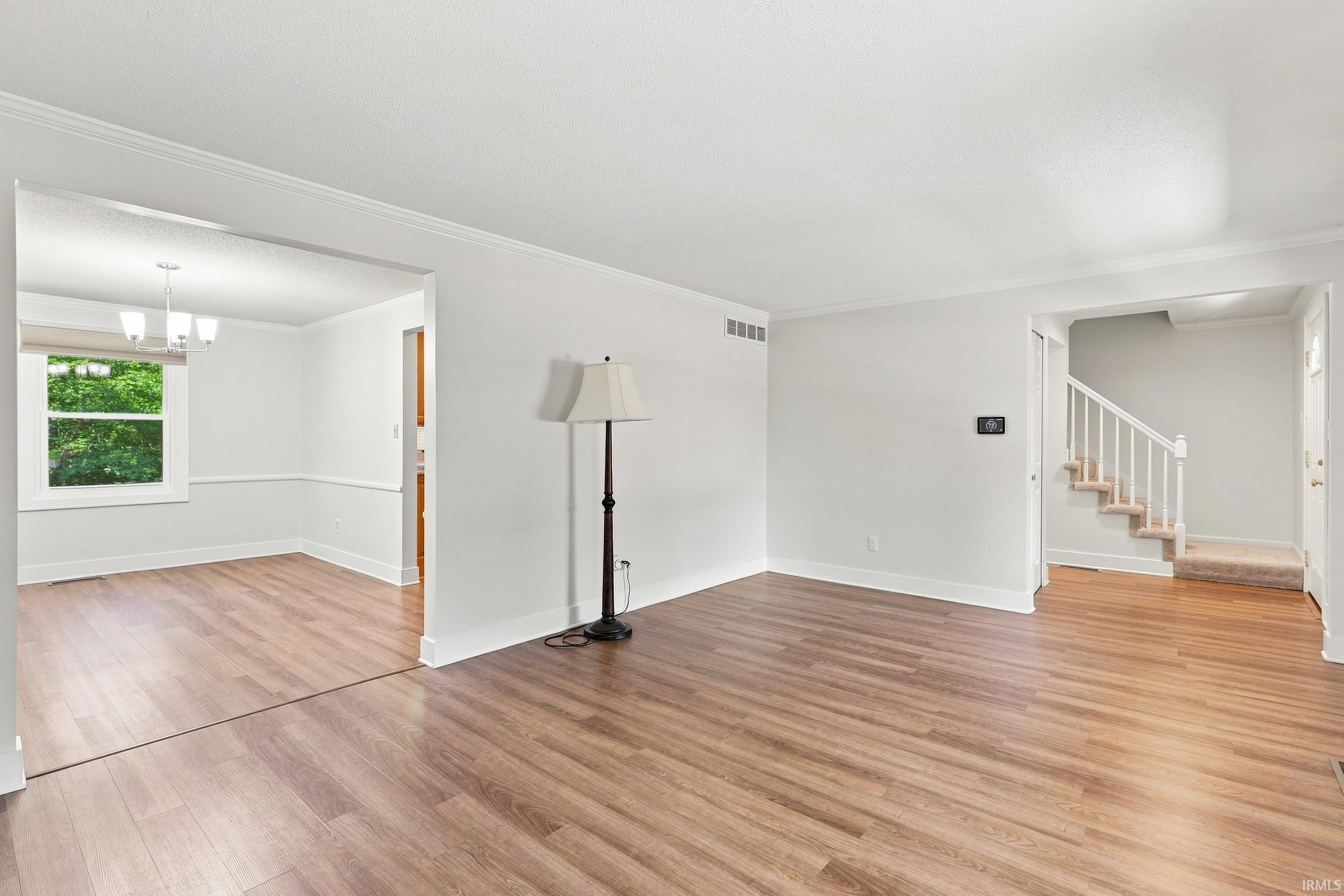 Spacious interior featuring wood-finish flooring, white trim, and crown molding