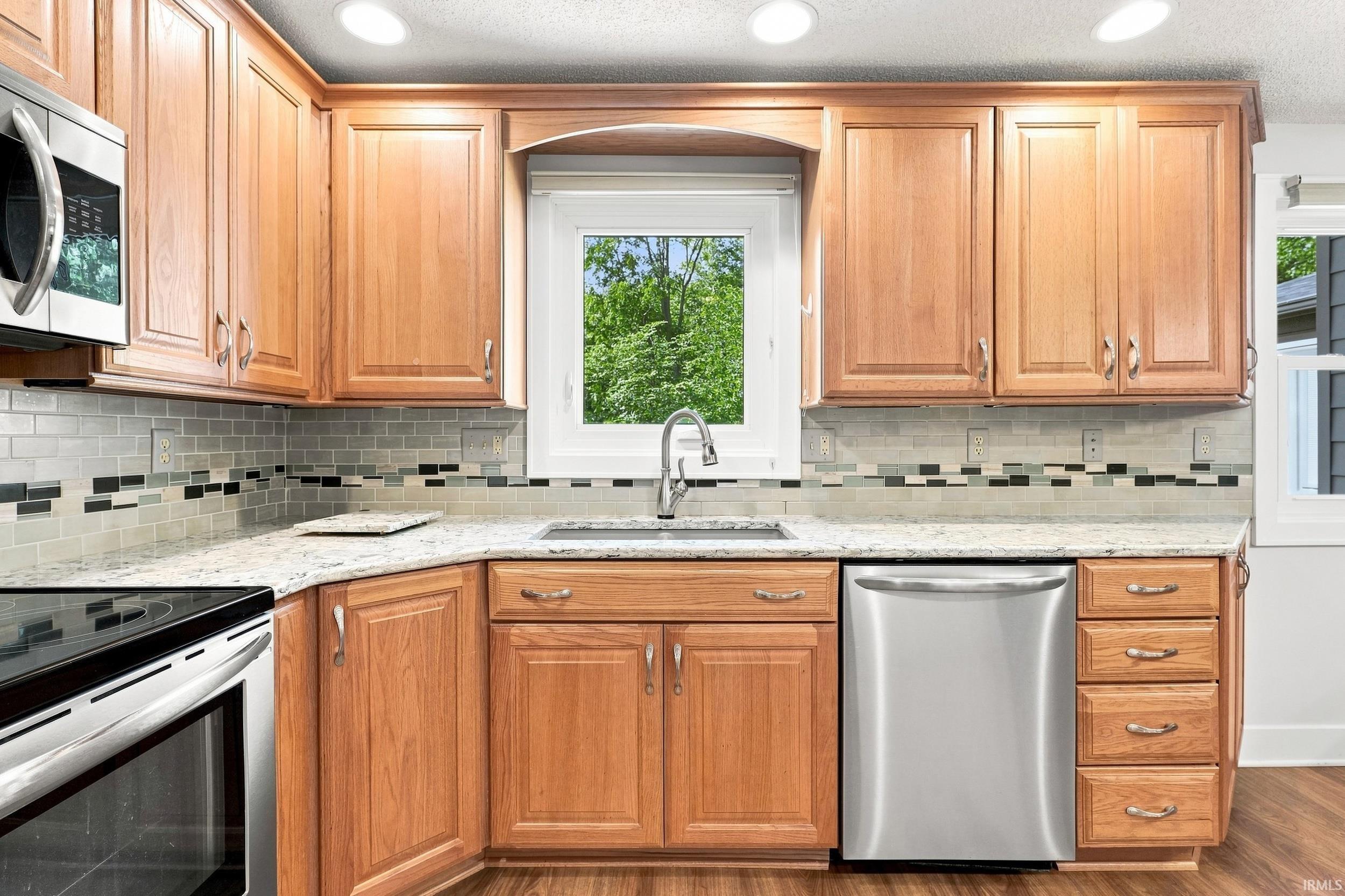 Kitchen featuring wood-finish cabinetry, light-toned countertops, and a patterned tile backsplash