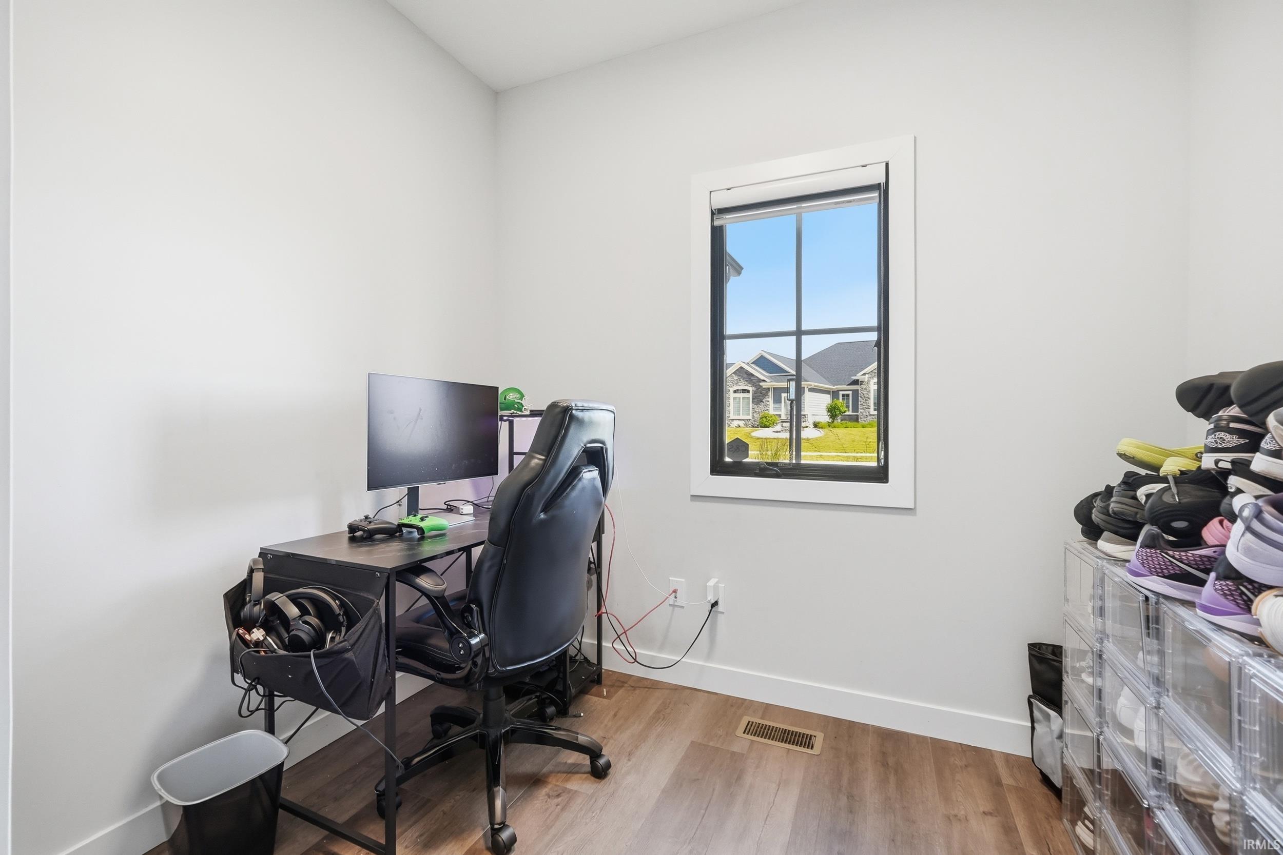 Room featuring wood-finish flooring, a single window with black framing and white trim, and light-toned walls