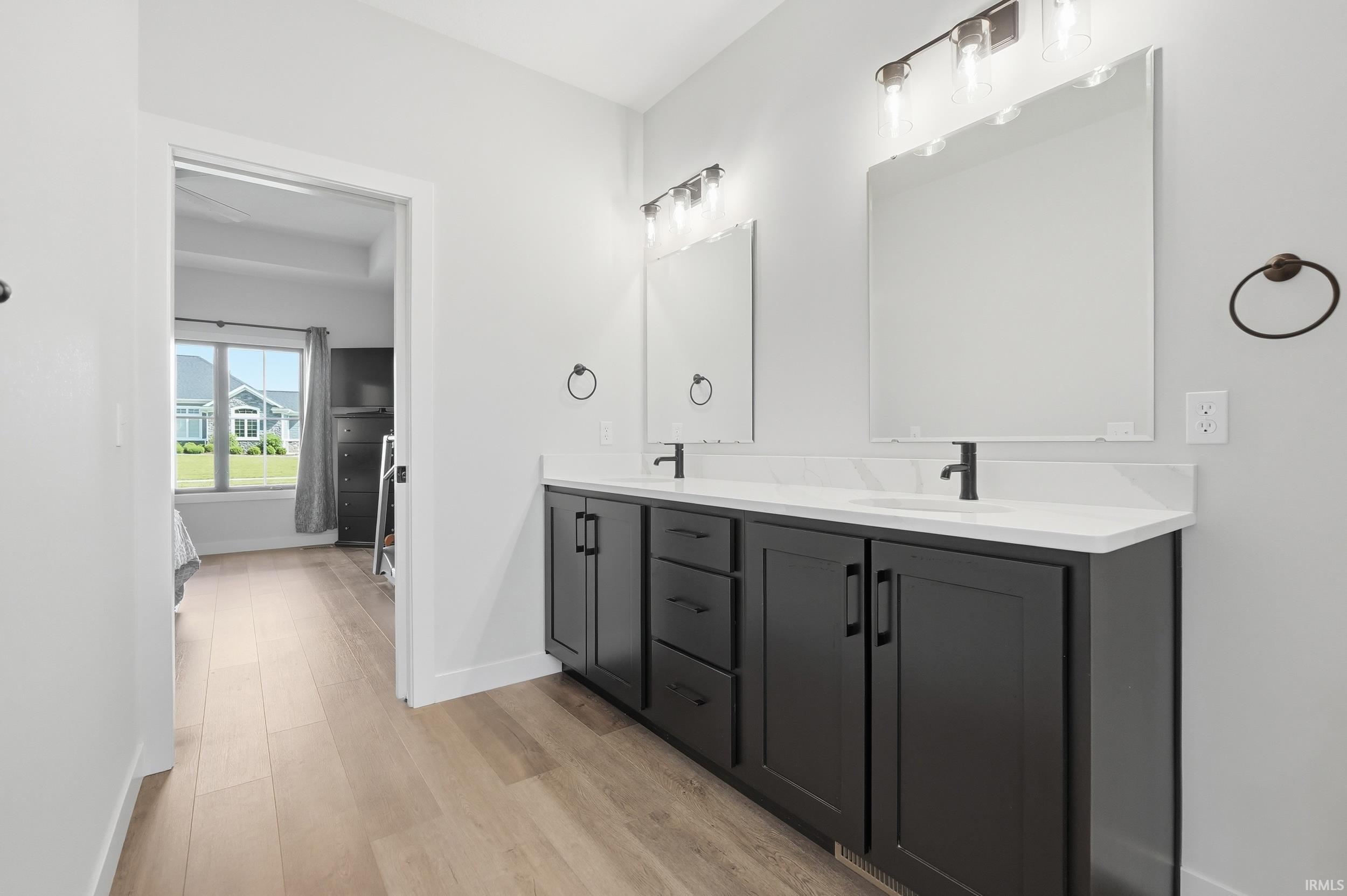 Spacious vanity area featuring dual sinks, dark cabinetry, and light countertops