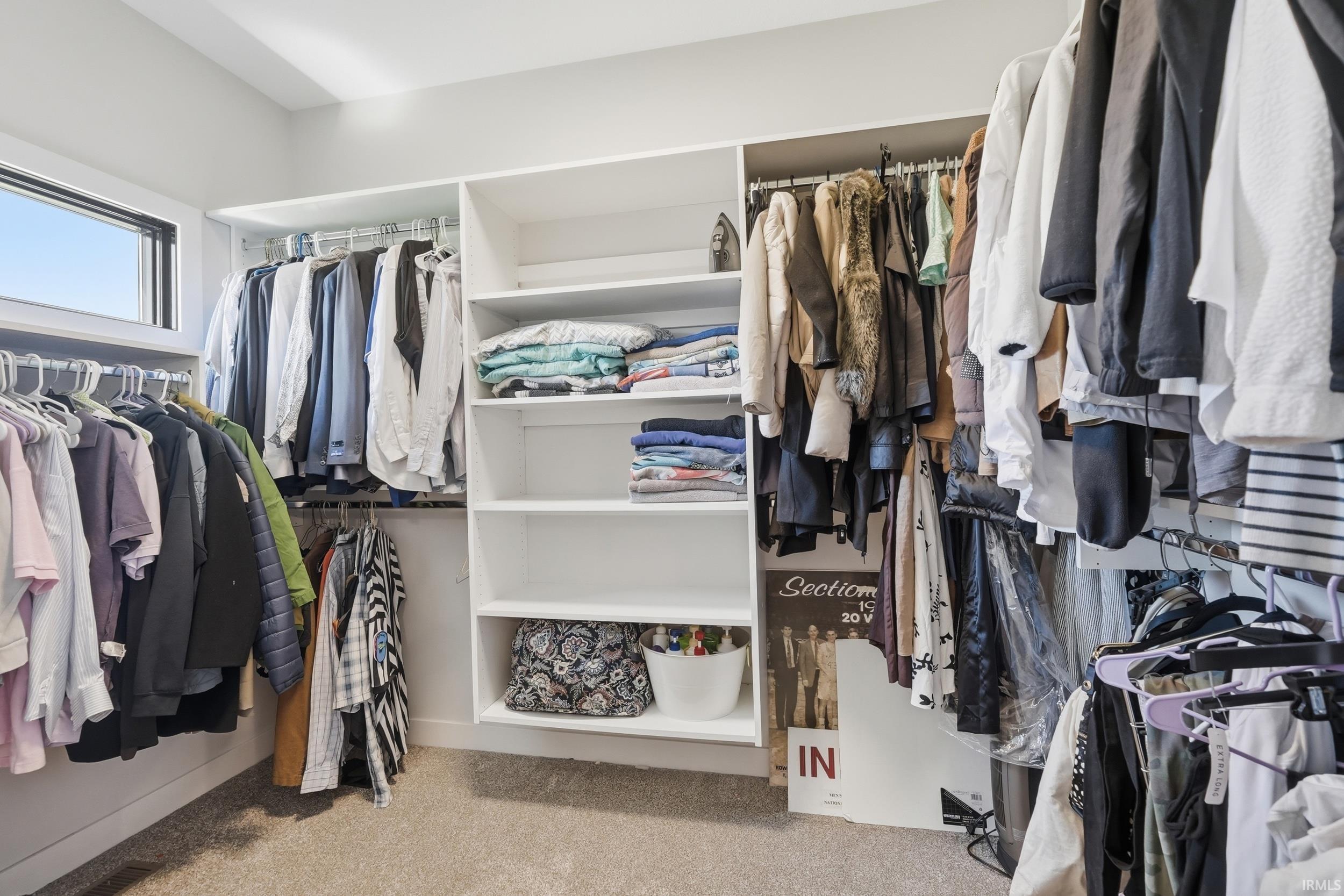 Walk-in closet featuring extensive built-in shelving, multiple hanging rods, and a window for natural light