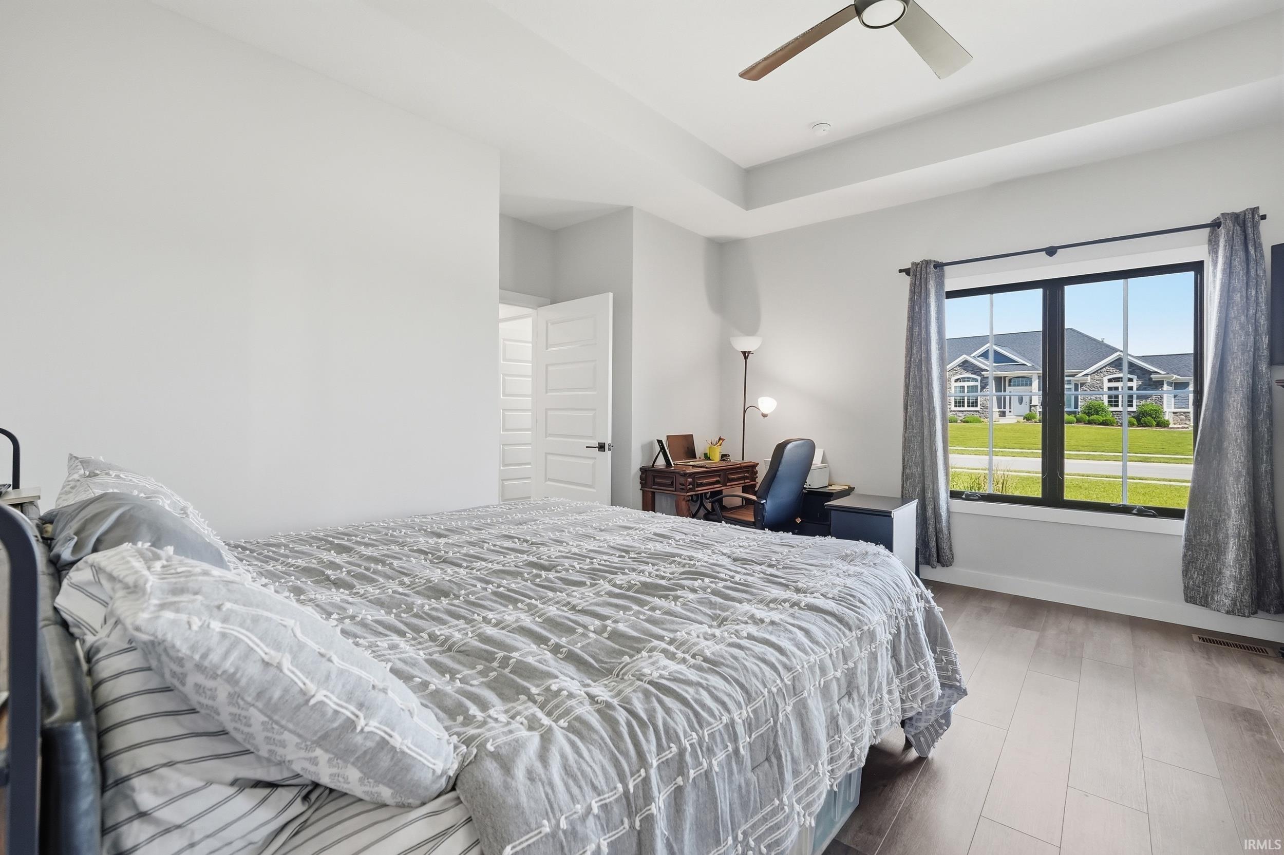 Spacious room featuring wood-finish flooring, a tray ceiling, and a ceiling fan