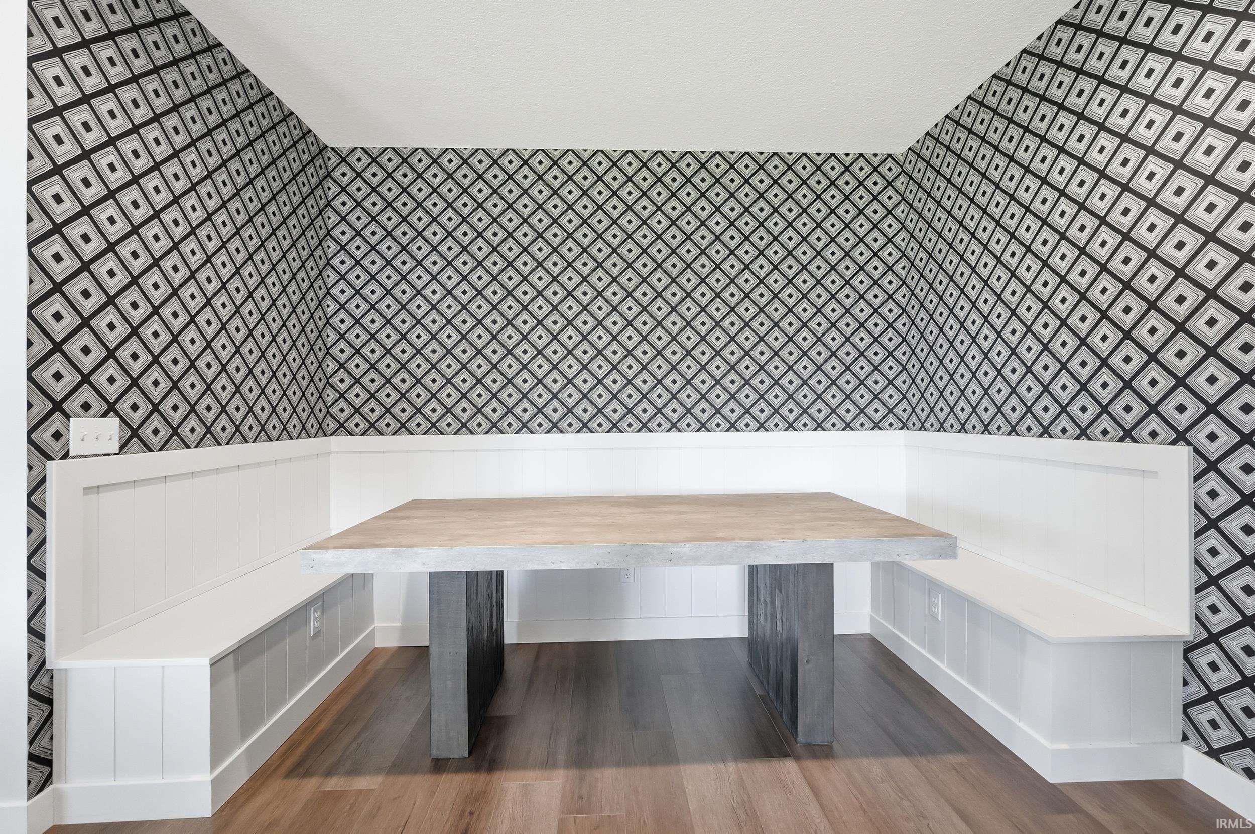 Built-in banquette seating with white wainscoting and storage bases, complemented by a concrete-finish table with dark gray legs