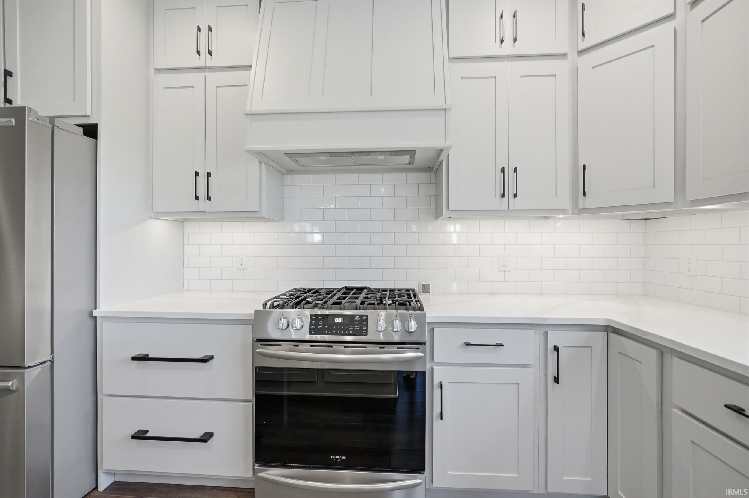 Kitchen featuring white shaker-style cabinetry with matte black hardware, white subway tile backsplash, and light-toned countertops