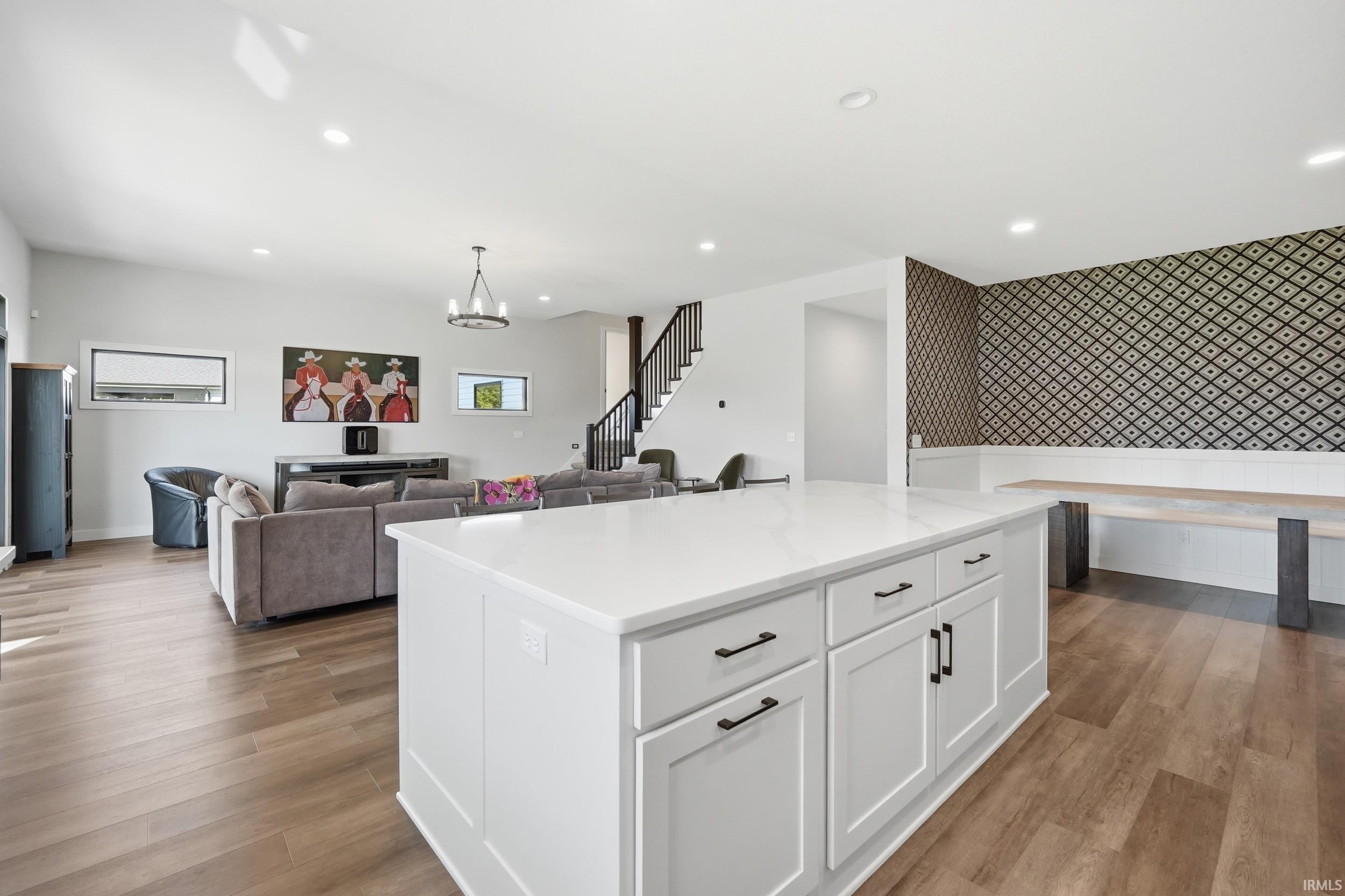 Expansive open-concept living space featuring a large kitchen island with white cabinetry and a light-toned countertop