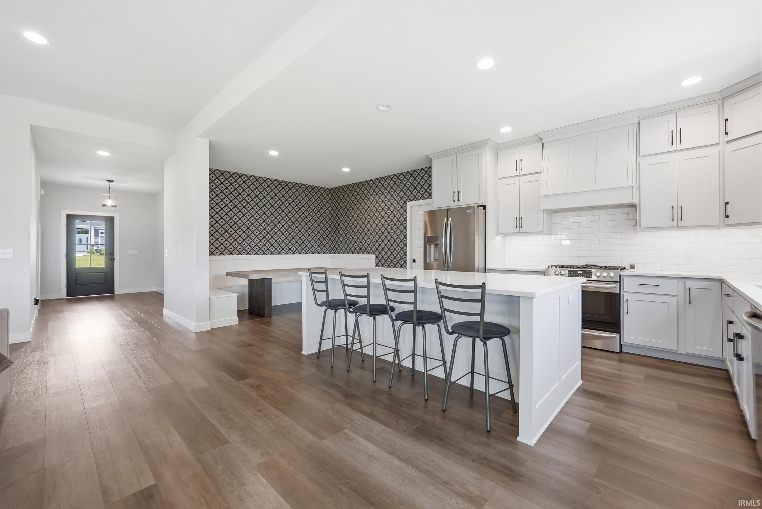 Open-concept kitchen and dining area featuring a central island with seating, extensive white cabinetry, and stainless steel appliances