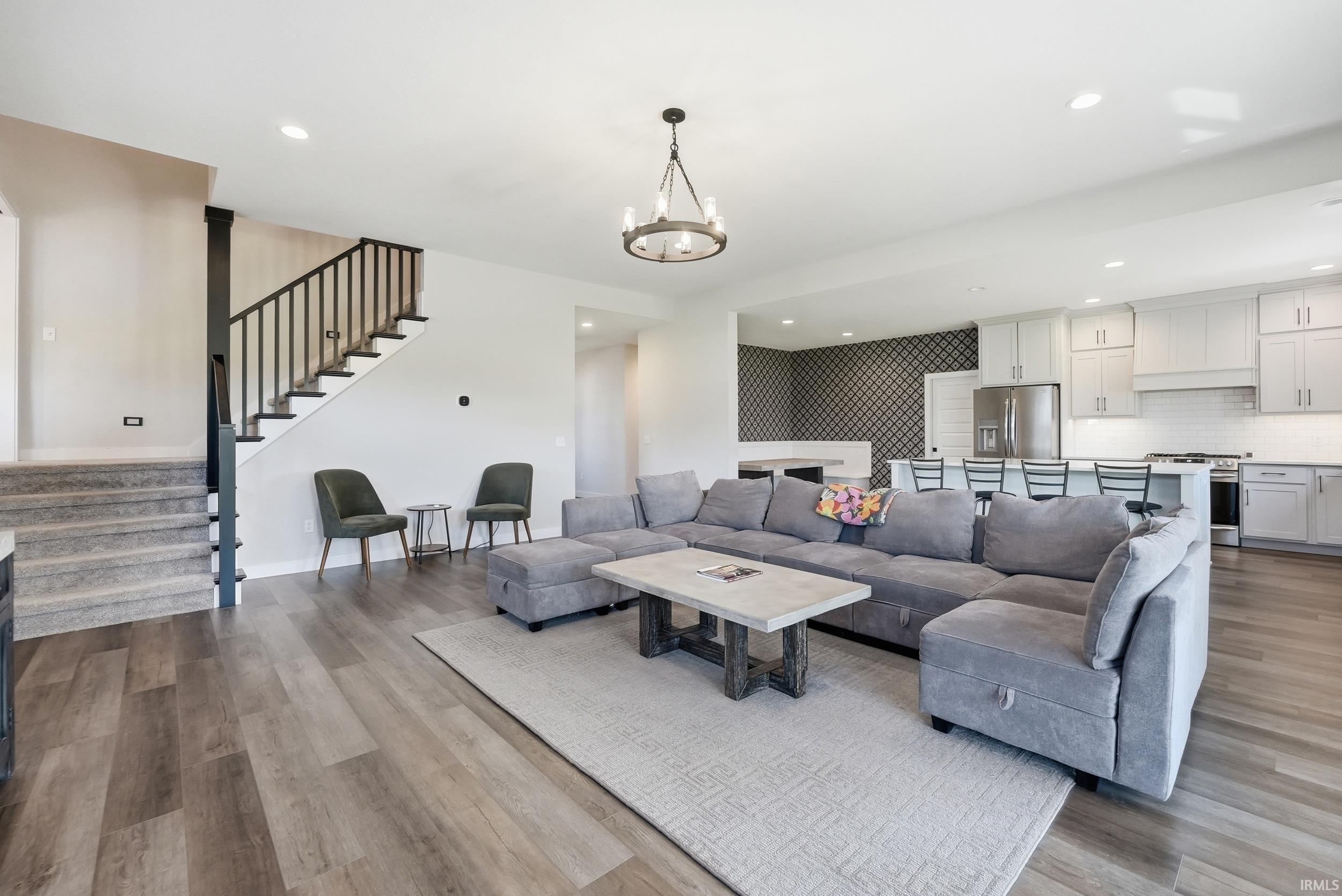 Open-concept living area featuring wood-finish flooring, recessed lighting, and a modern chandelier