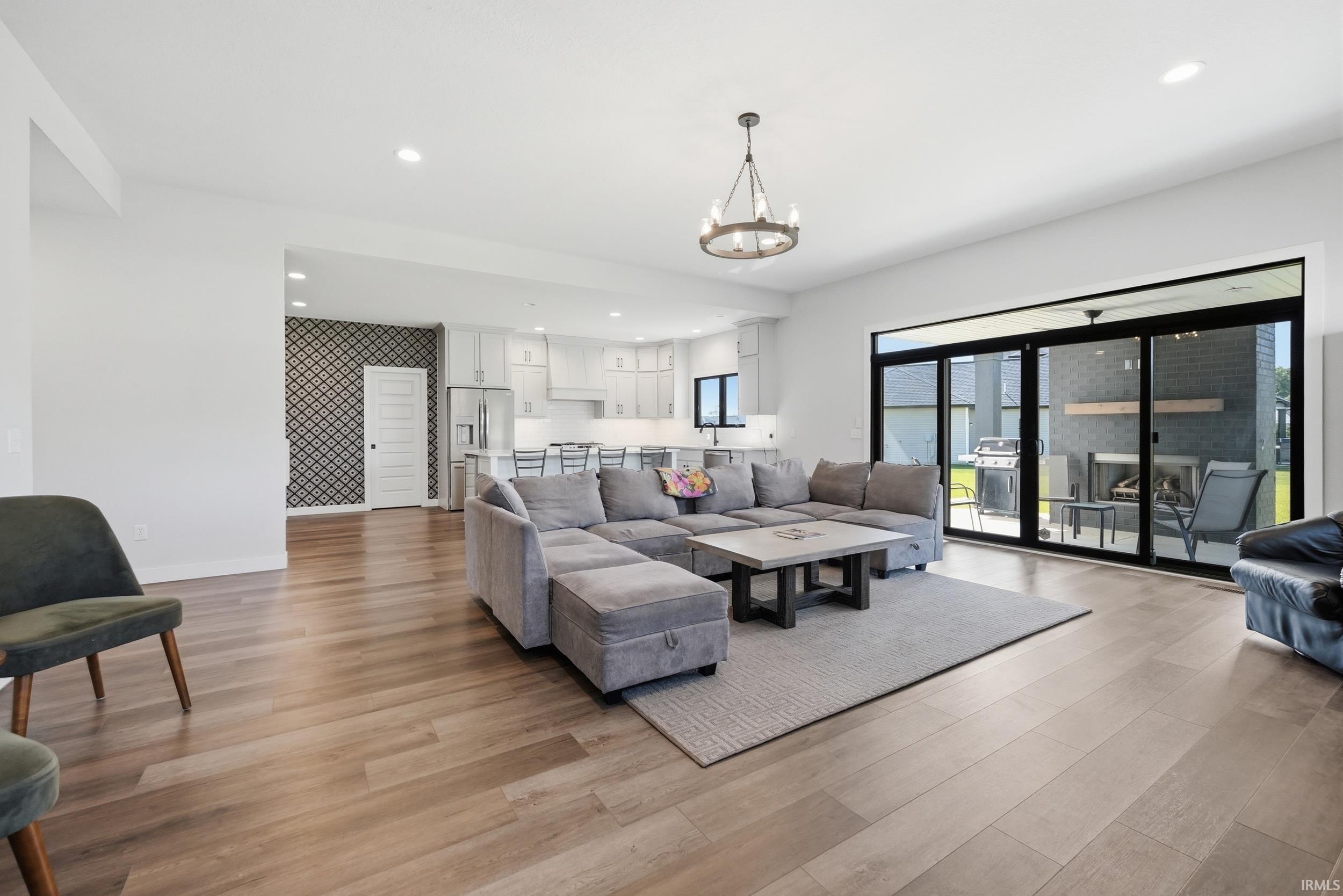 Open-concept living space featuring wood-finish flooring, a contemporary chandelier, and a black framed multi-panel sliding door