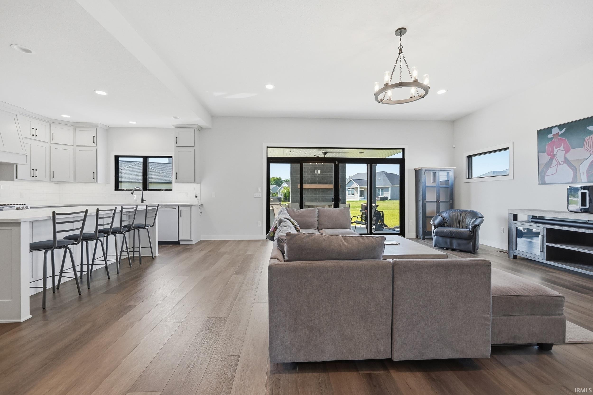 Open-concept living space featuring wood-finish flooring, recessed lighting, and a modern chandelier