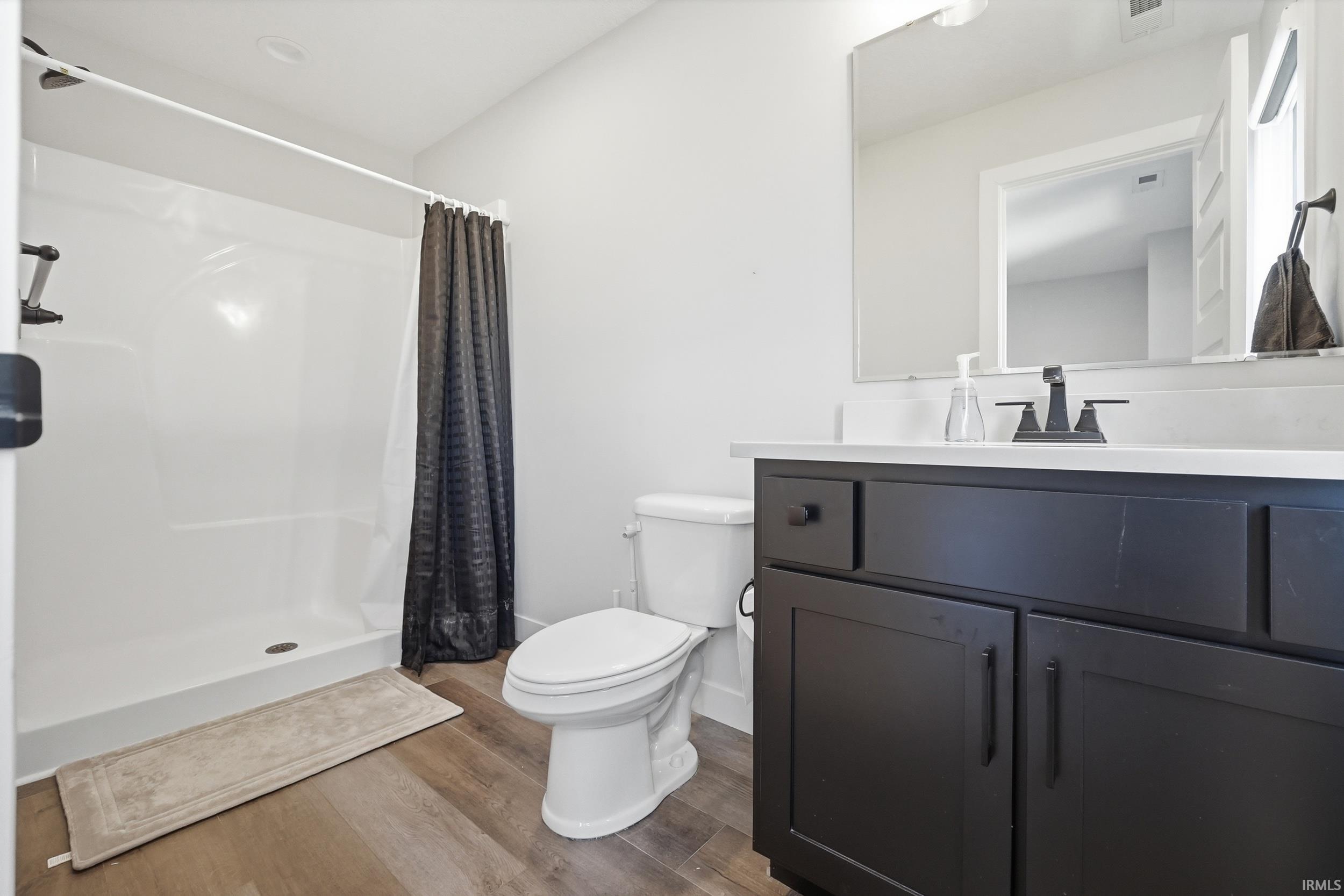 Contemporary bathroom featuring a dark wood-finish vanity with a white countertop and rectangular sink