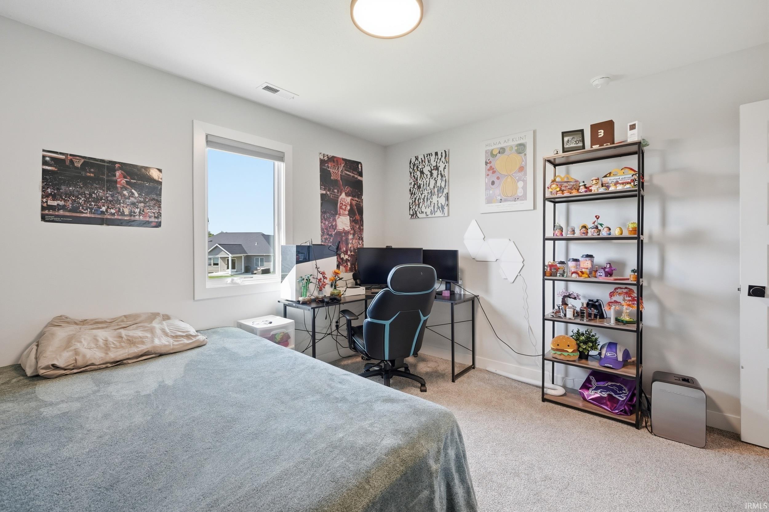 Bedroom featuring light gray walls, plush carpet flooring, a large window, and a built-in ceiling light fixture