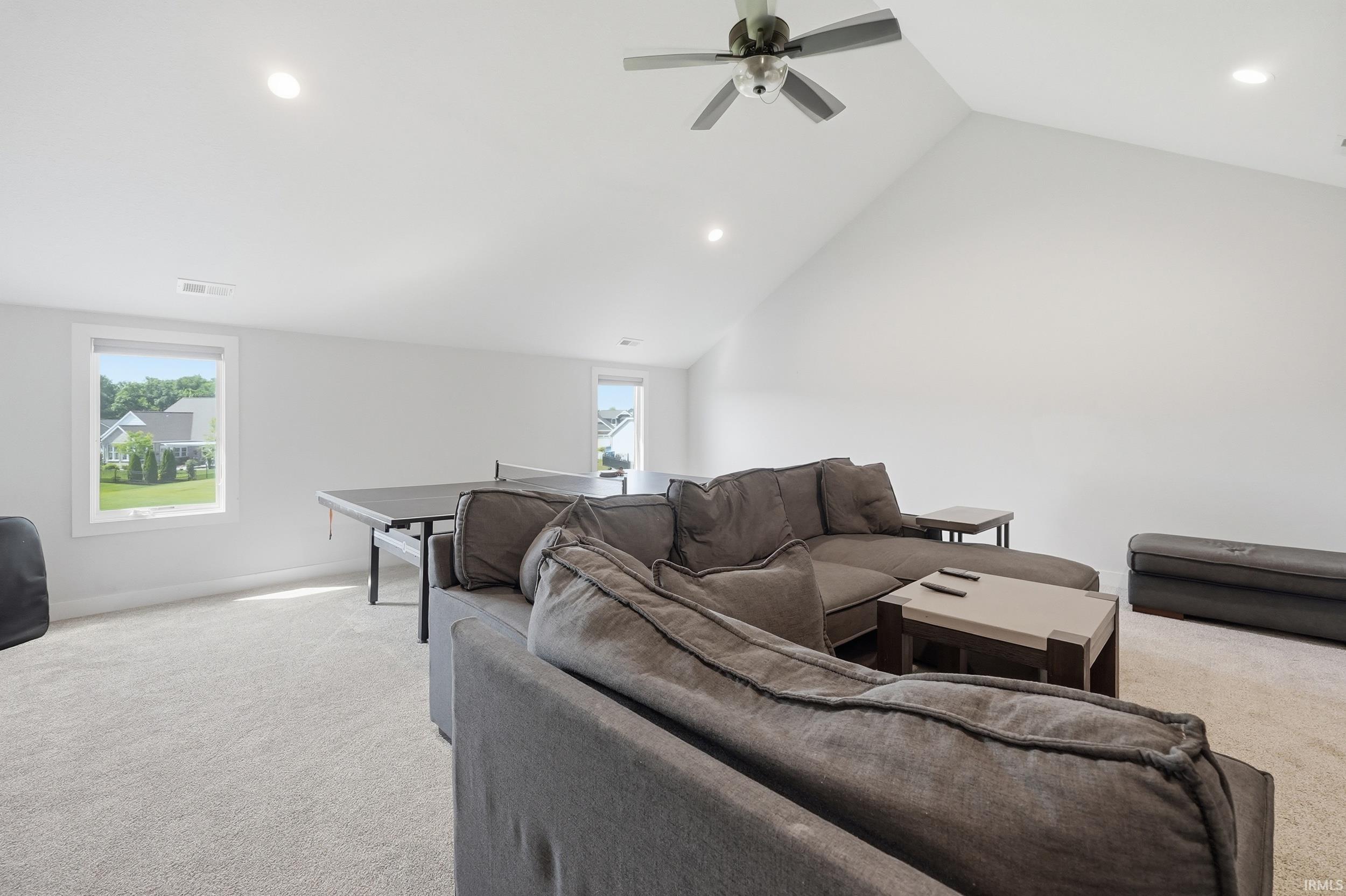 Spacious room featuring a vaulted ceiling with a ceiling fan, recessed lighting, and soft carpeting