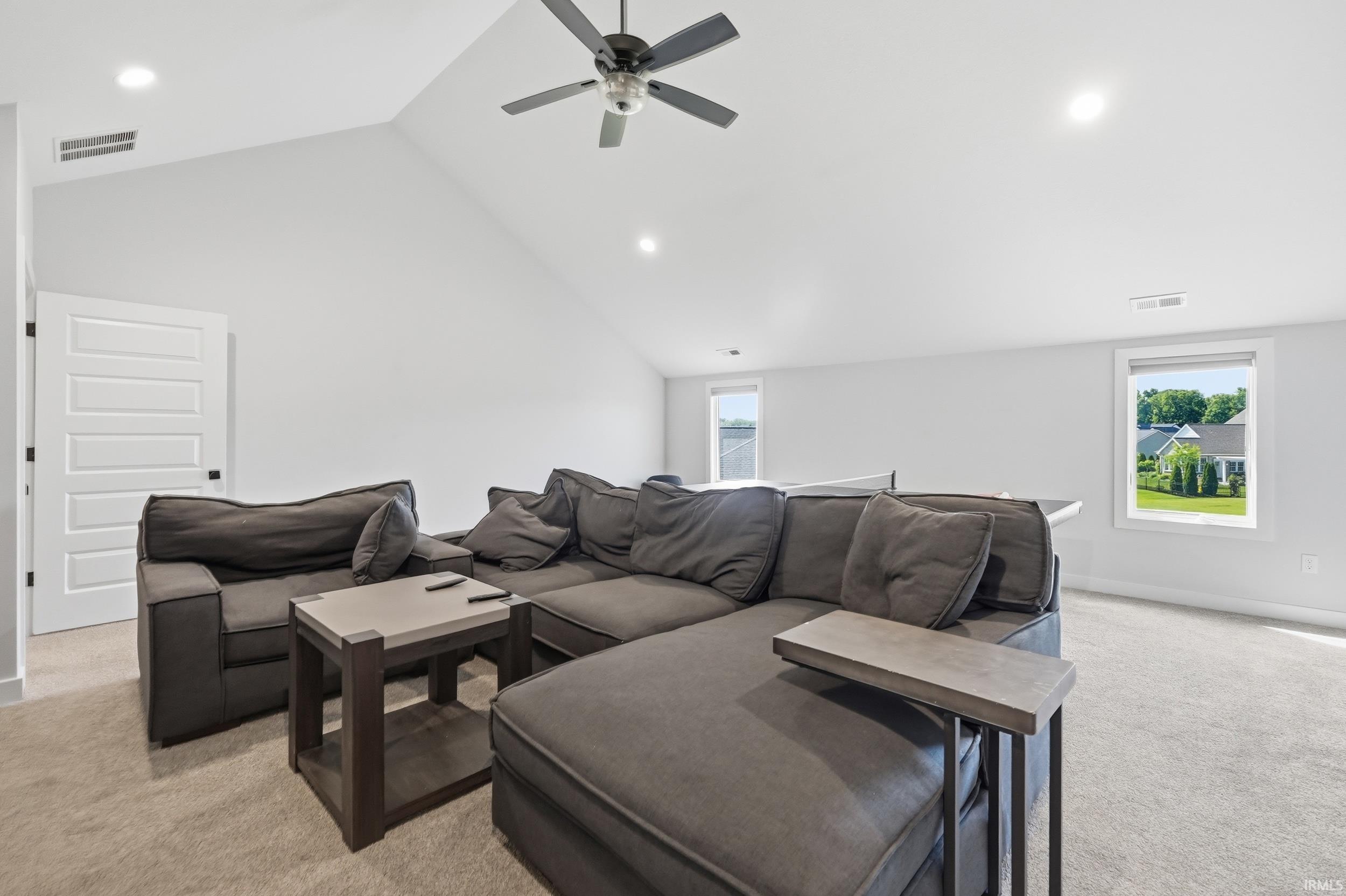 Spacious bonus room featuring an angled vaulted ceiling, recessed lighting, and a modern ceiling fan