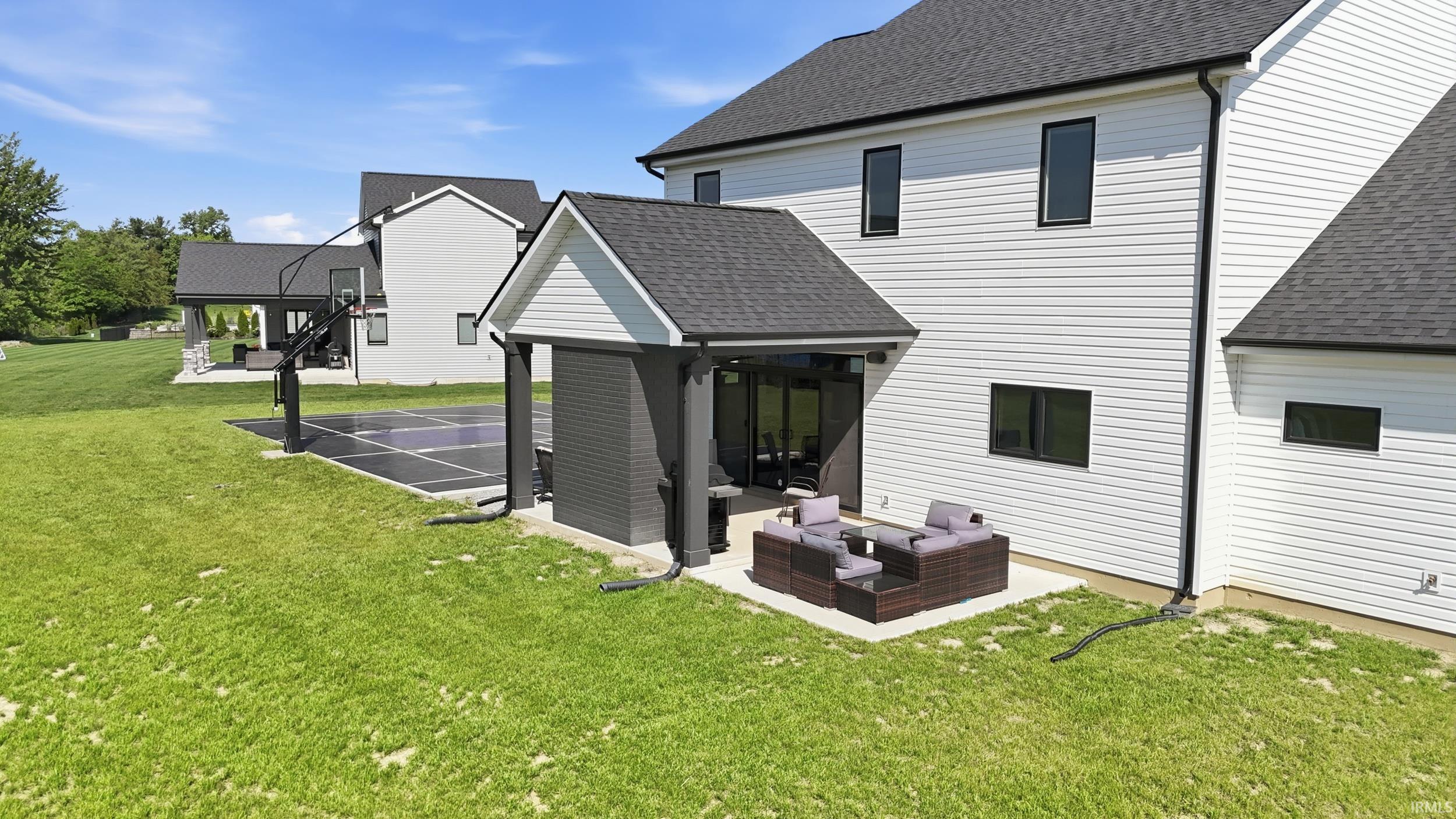 Modern white siding exterior with dark trim windows, featuring a covered patio with direct access to interior spaces