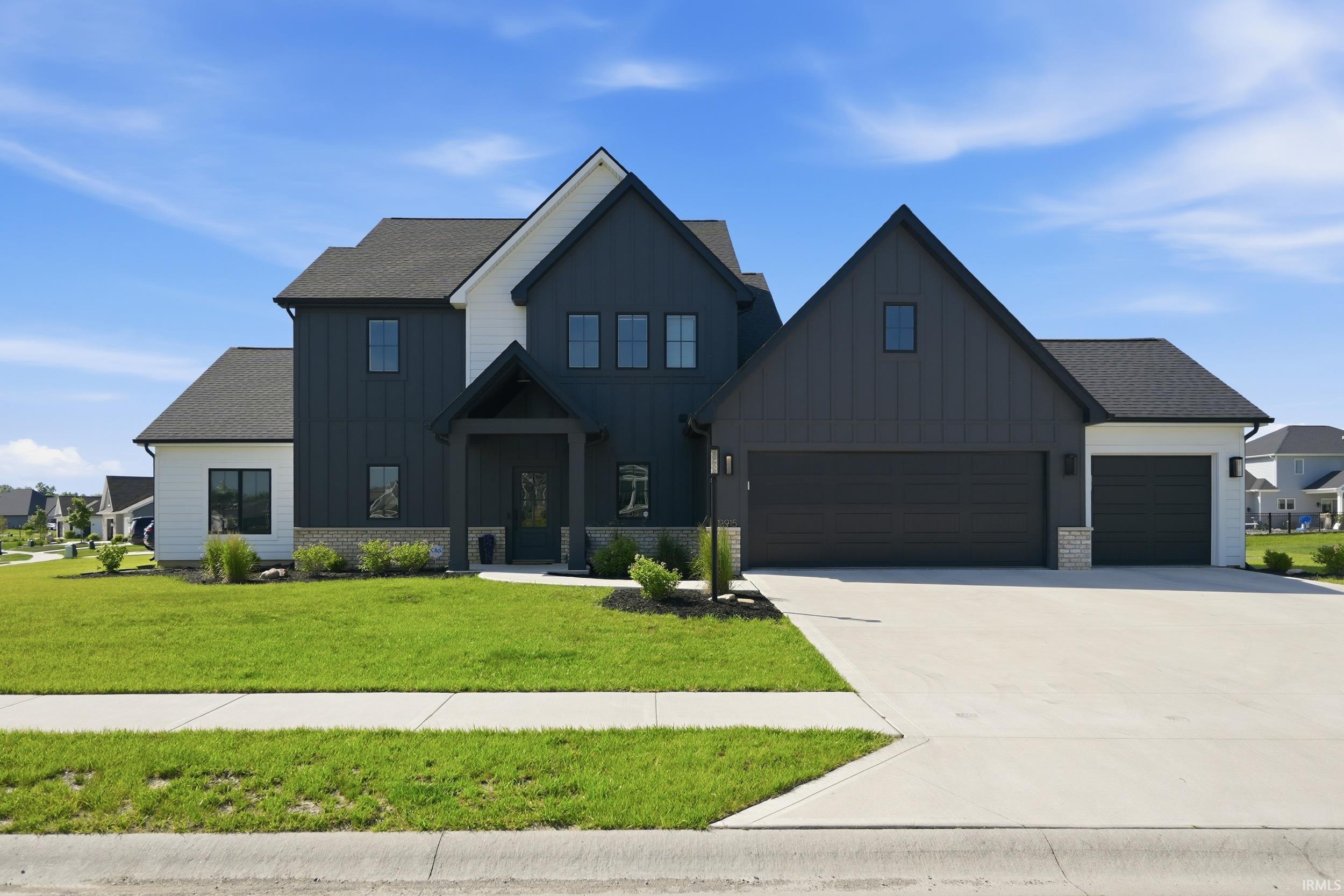 Contemporary two-story exterior featuring dark board and batten siding with white trim accents and a contrasting dark roof