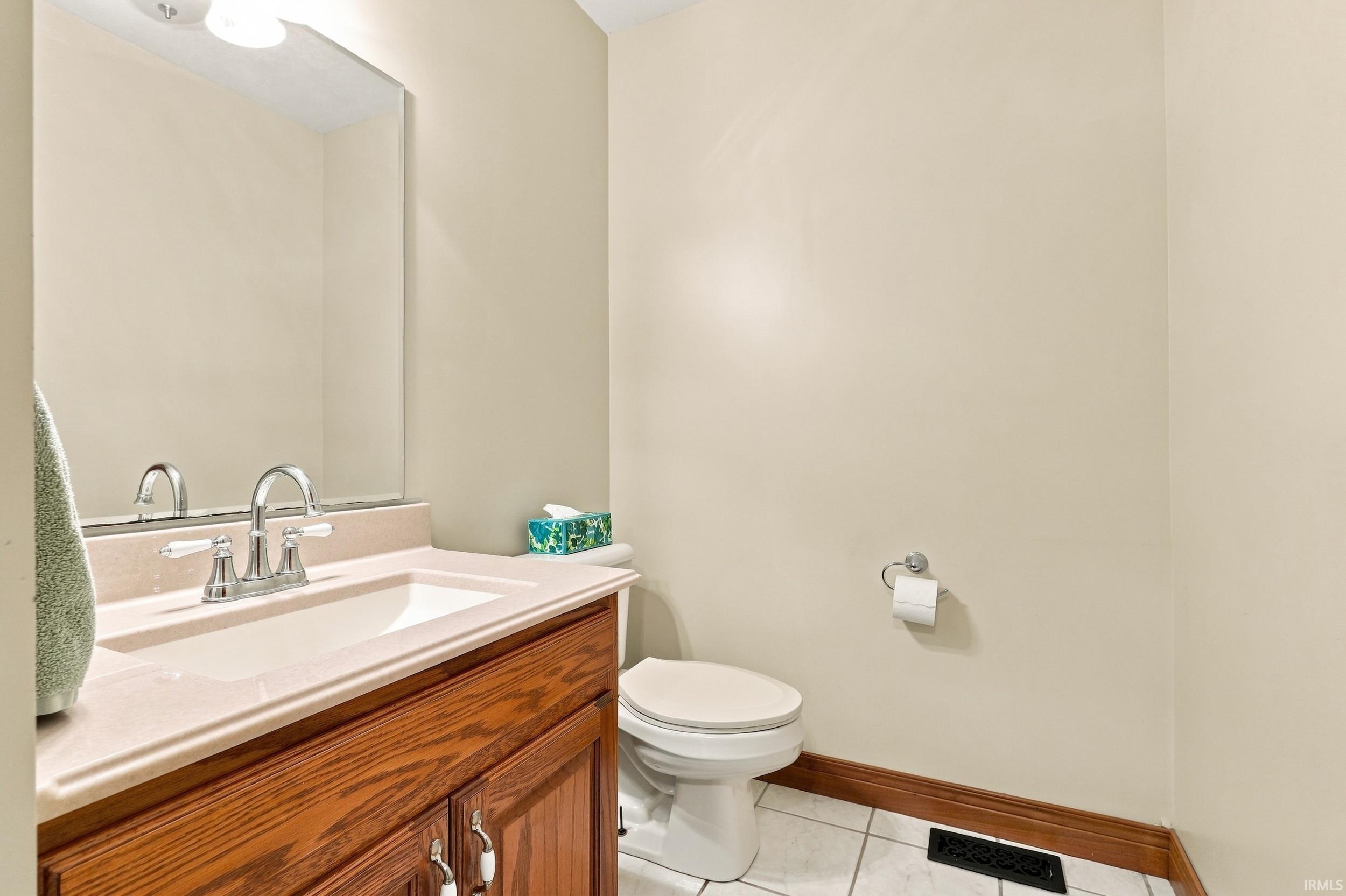 Bathroom featuring an oak wood-finish vanity with a light-toned countertop, an undermount sink, and a chrome faucet