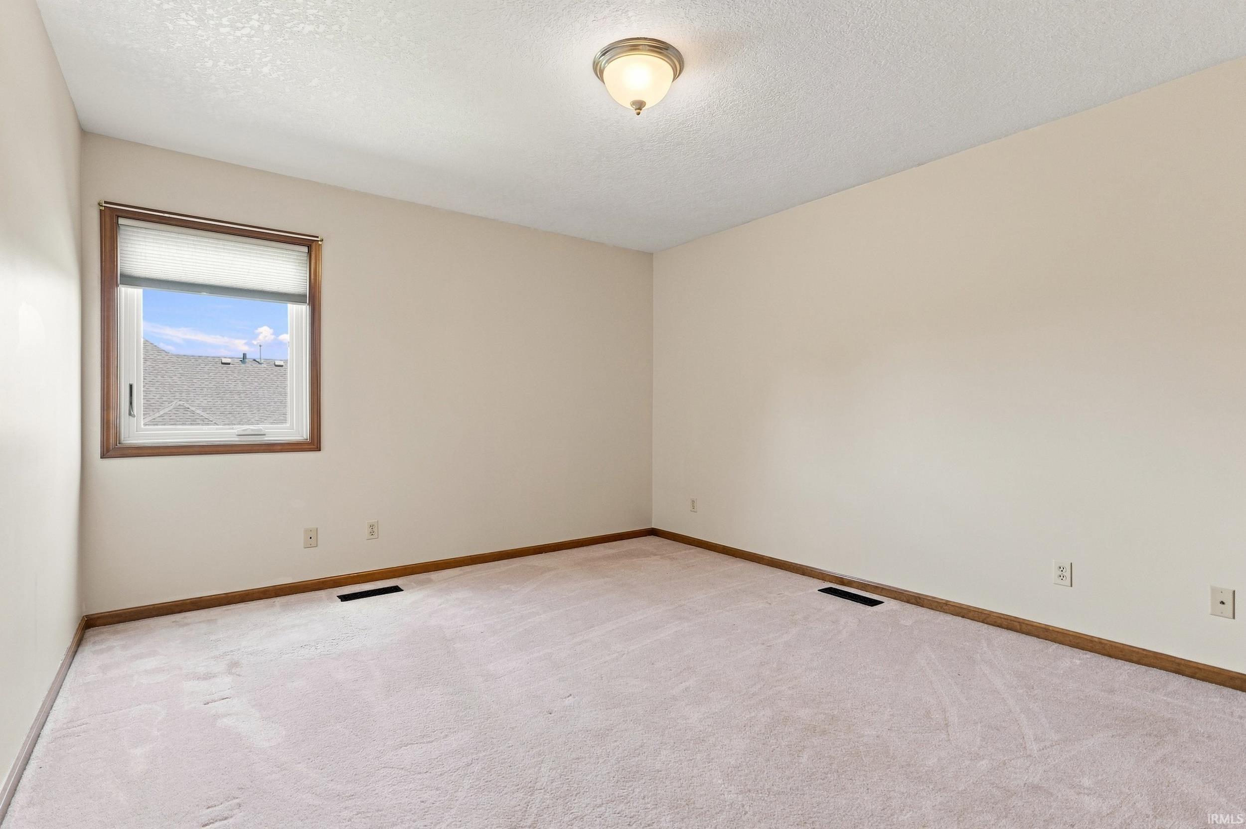Neutral wall finishes with a single window featuring wood trim