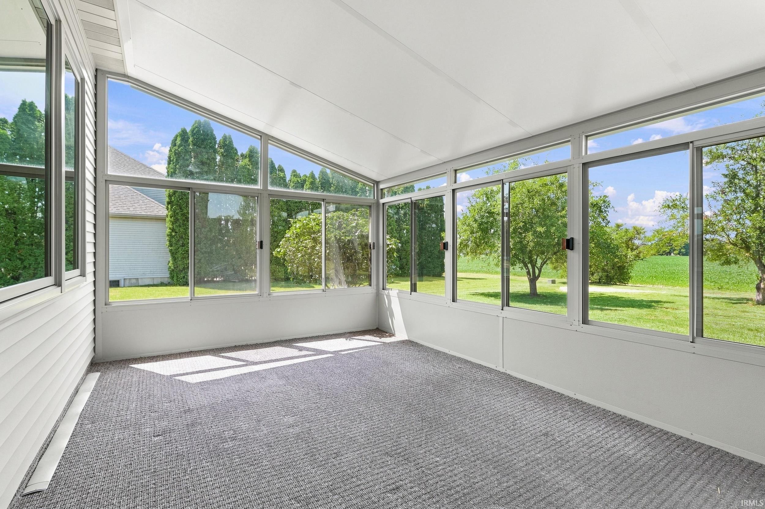 Sunroom featuring expansive windows, a sloped ceiling, and gray textured carpeting