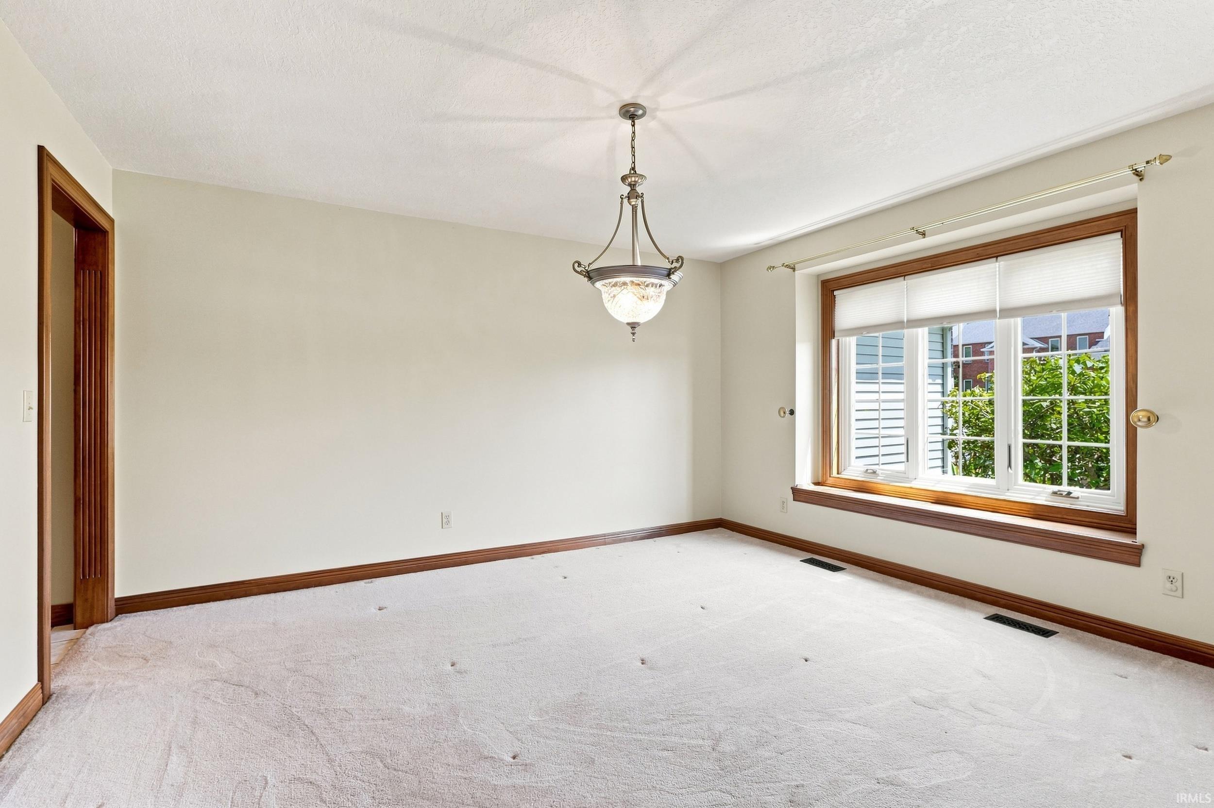 Interior room featuring light-colored carpet flooring, white walls, and a large window with white blinds