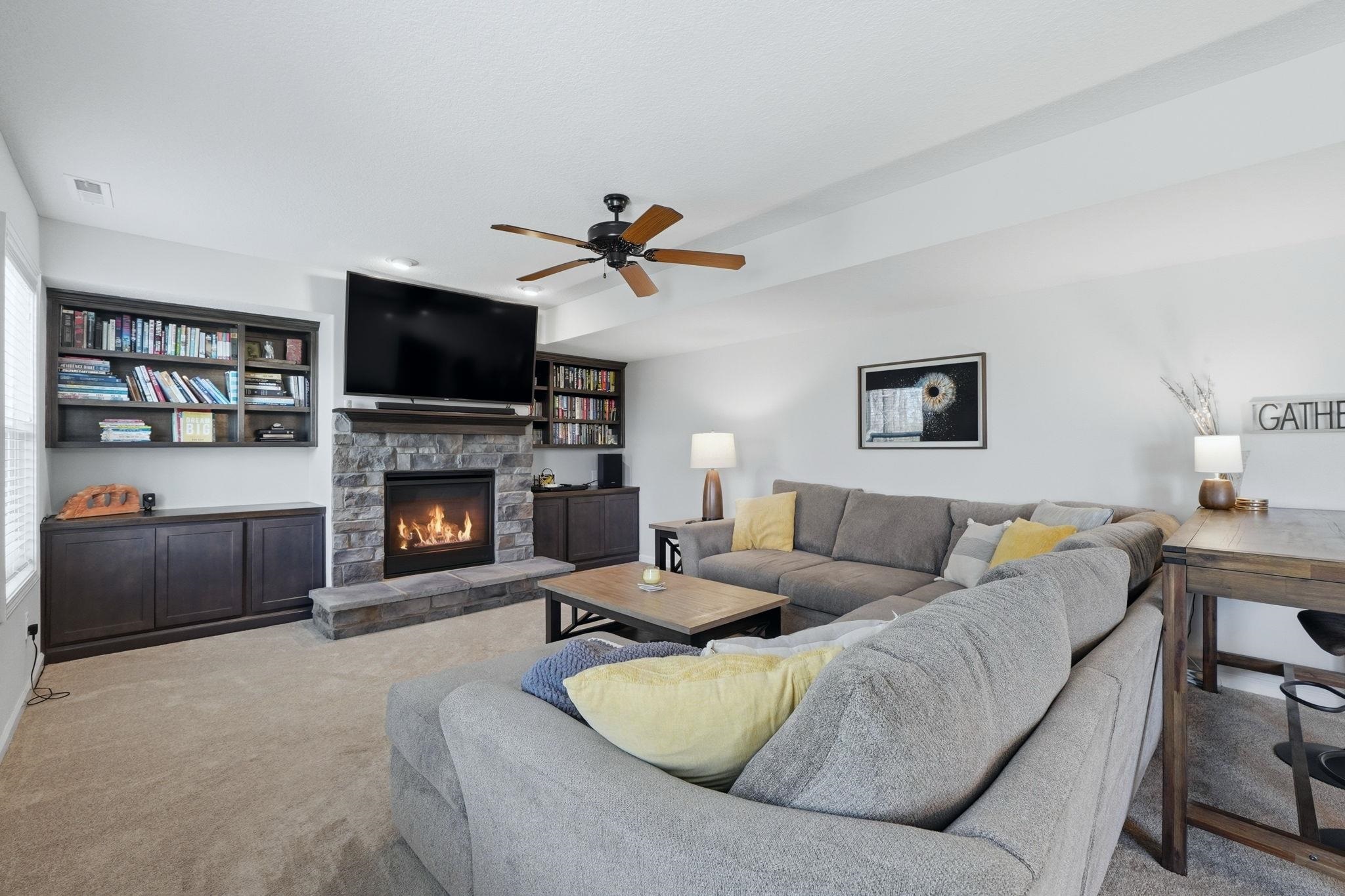 Family room featuring carpet, a fireplace, and a ceiling fan