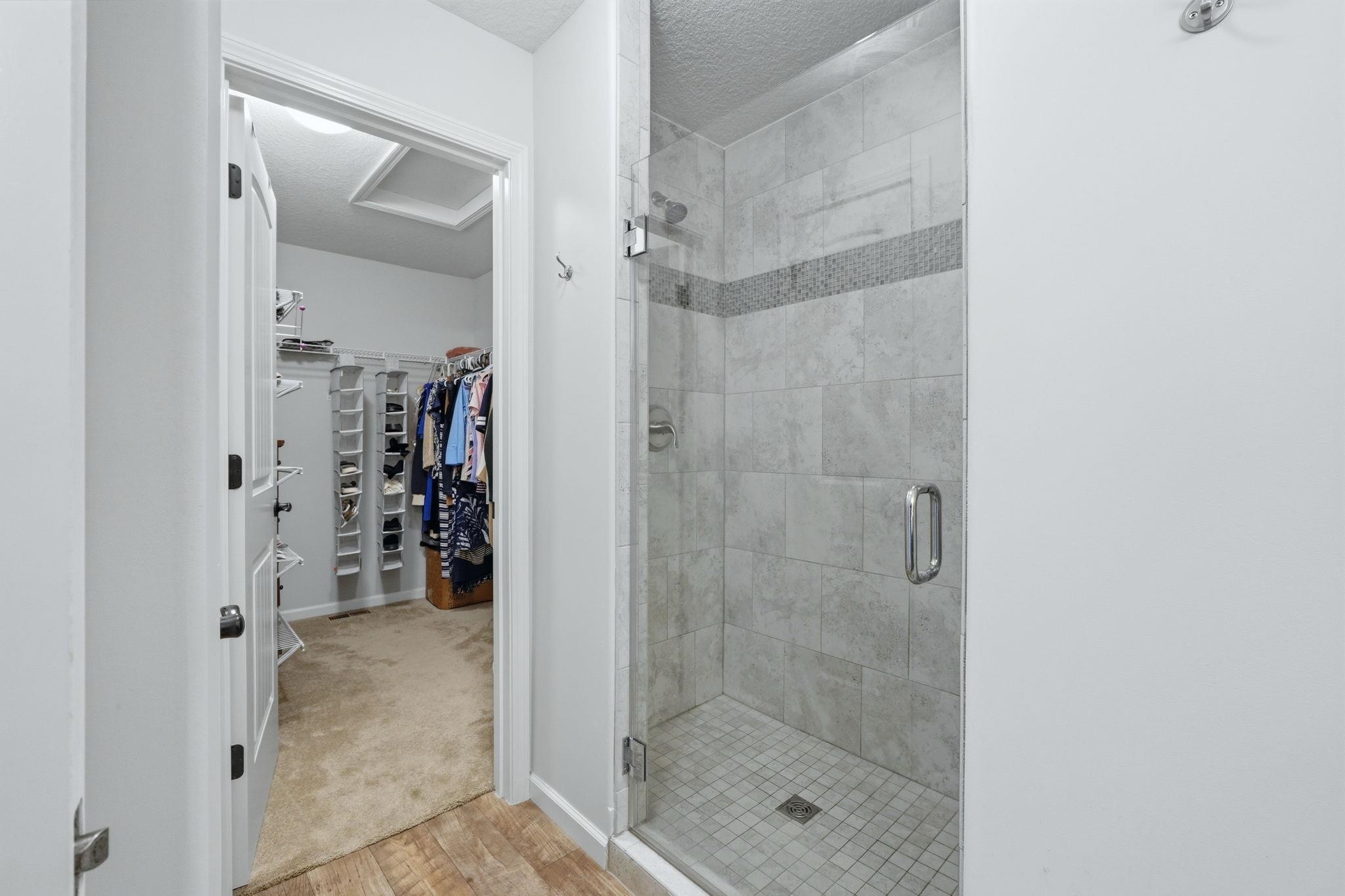 Bathroom featuring a spacious closet, a stall shower.