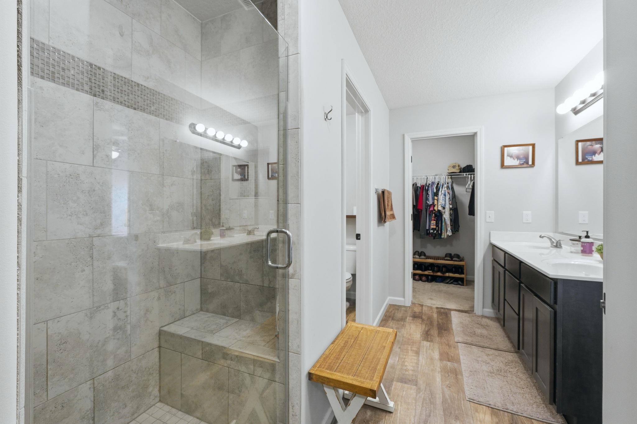 Glass-enclosed shower with a tiled bench and mosaic accent band