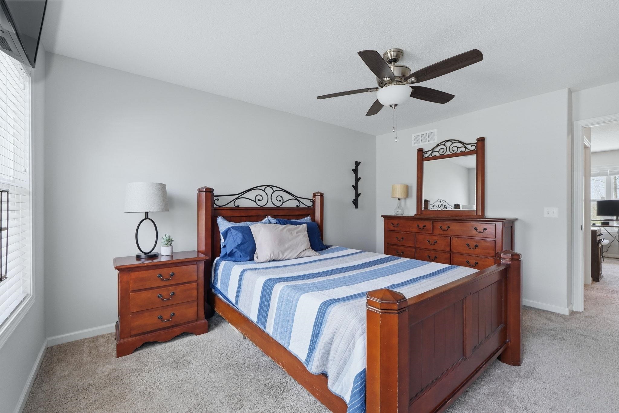 Bedroom with light colored carpet and a ceiling fan
