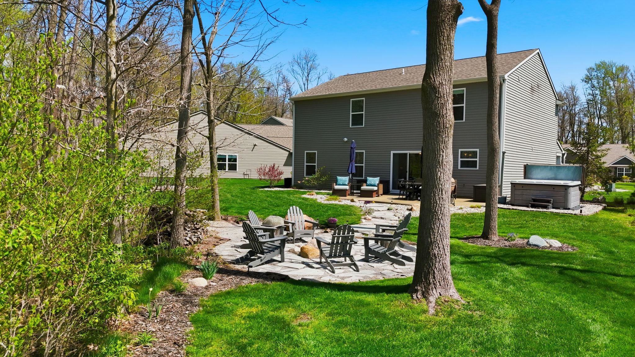Rear view of house featuring a patio area, an outdoor fire pit and a hot tub