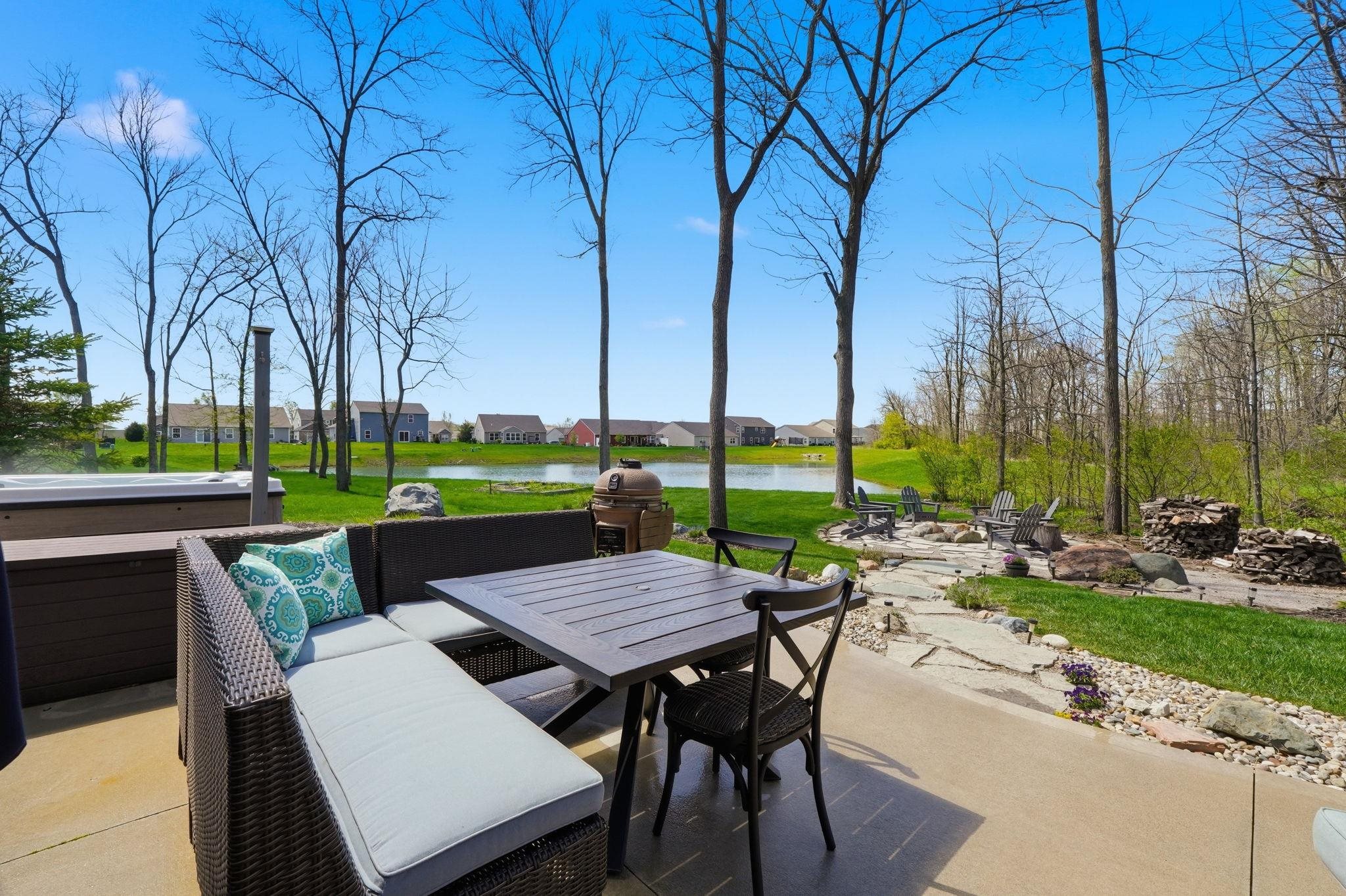 Expansive concrete patio offering a hot tub, a fire pit area with flagstone stepping stones, and direct water frontage