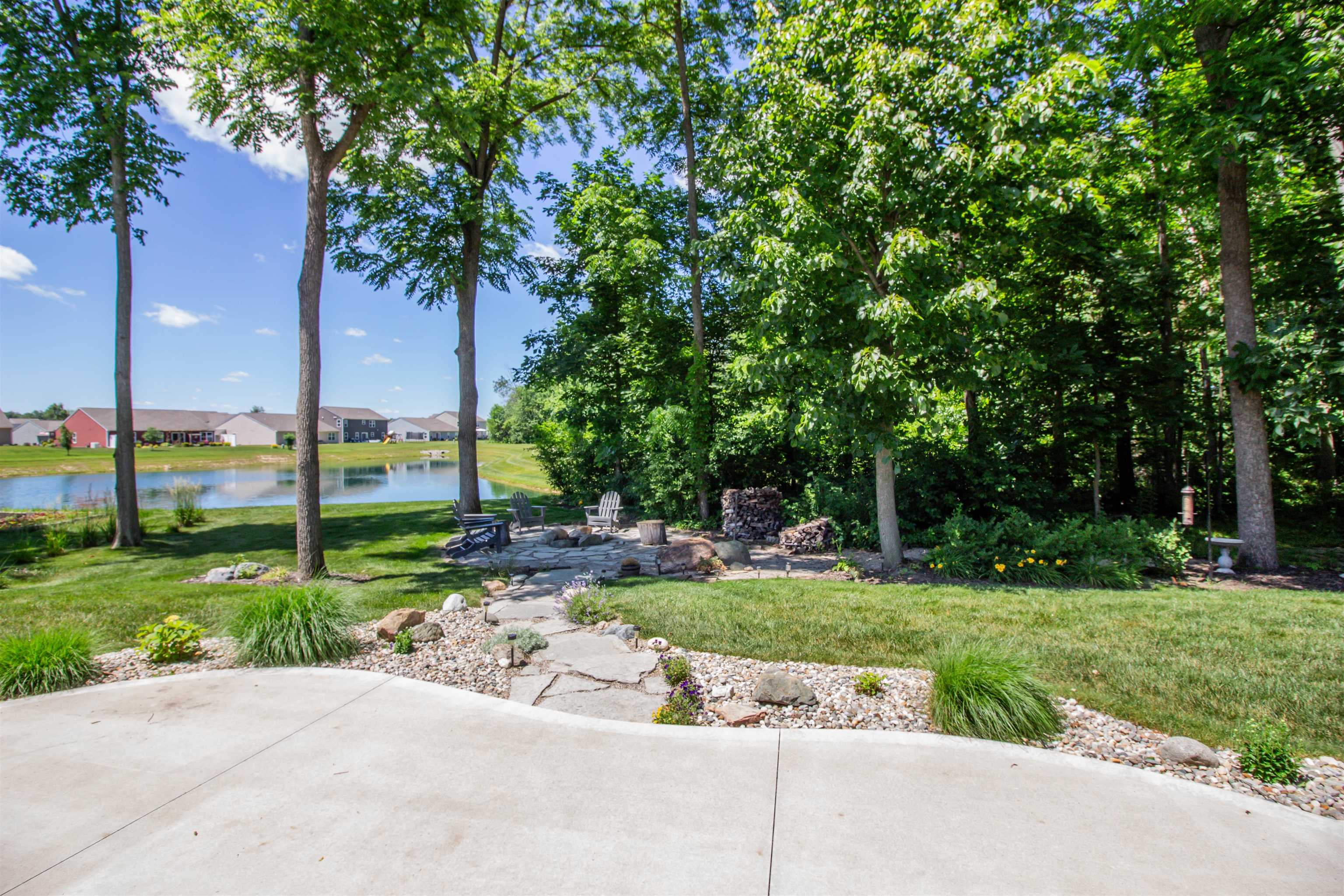 Expansive backyard featuring a concrete patio, a stone pathway, and a fire pit area