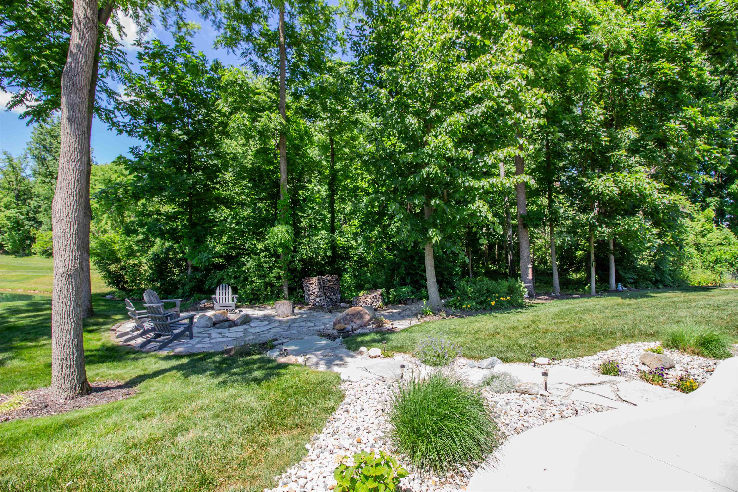 Expansive outdoor living area featuring a flagstone patio, a fire pit, and mature trees providing natural screening