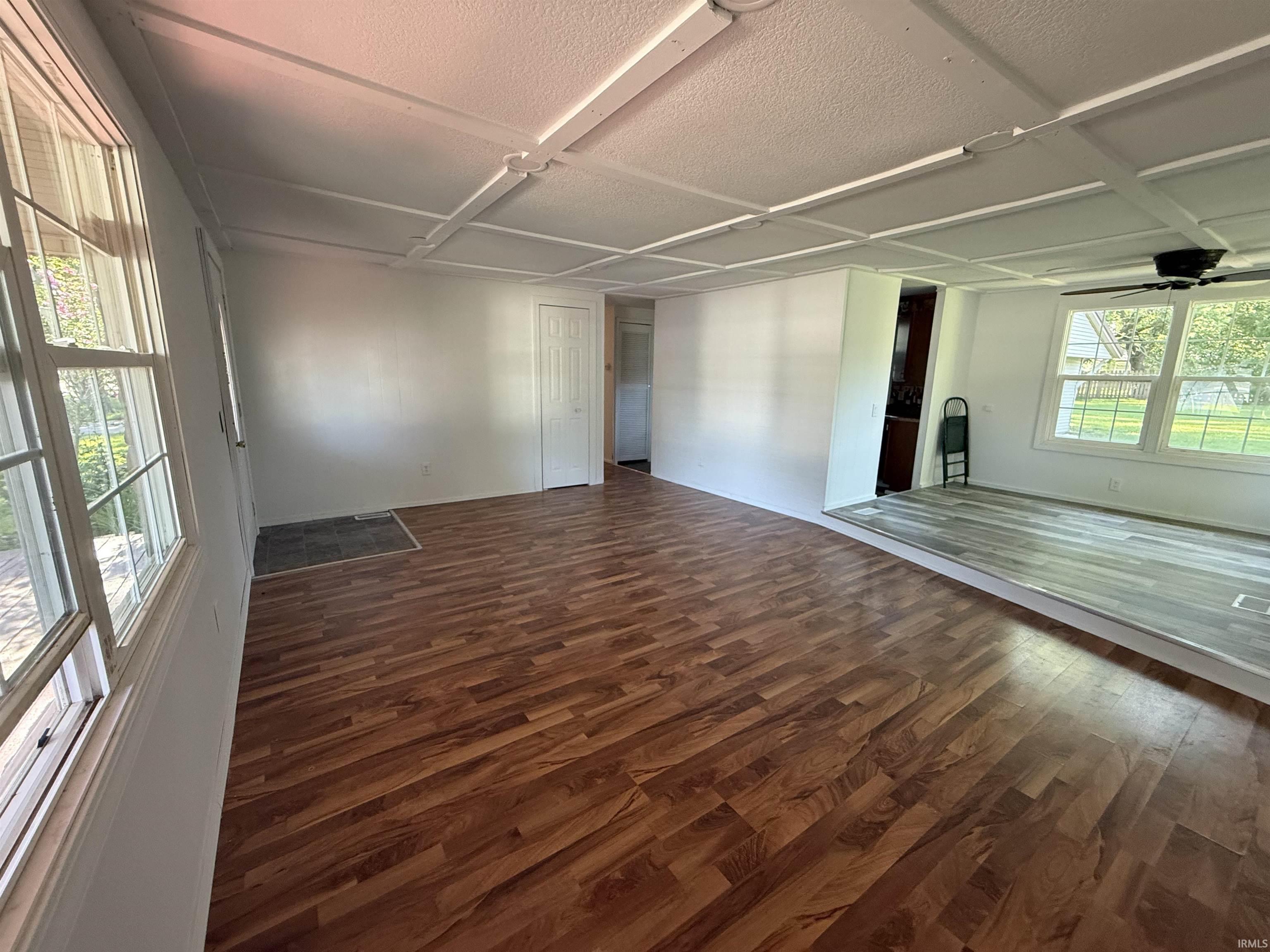 Spacious interior featuring wood-finish flooring, white walls, and multiple windows