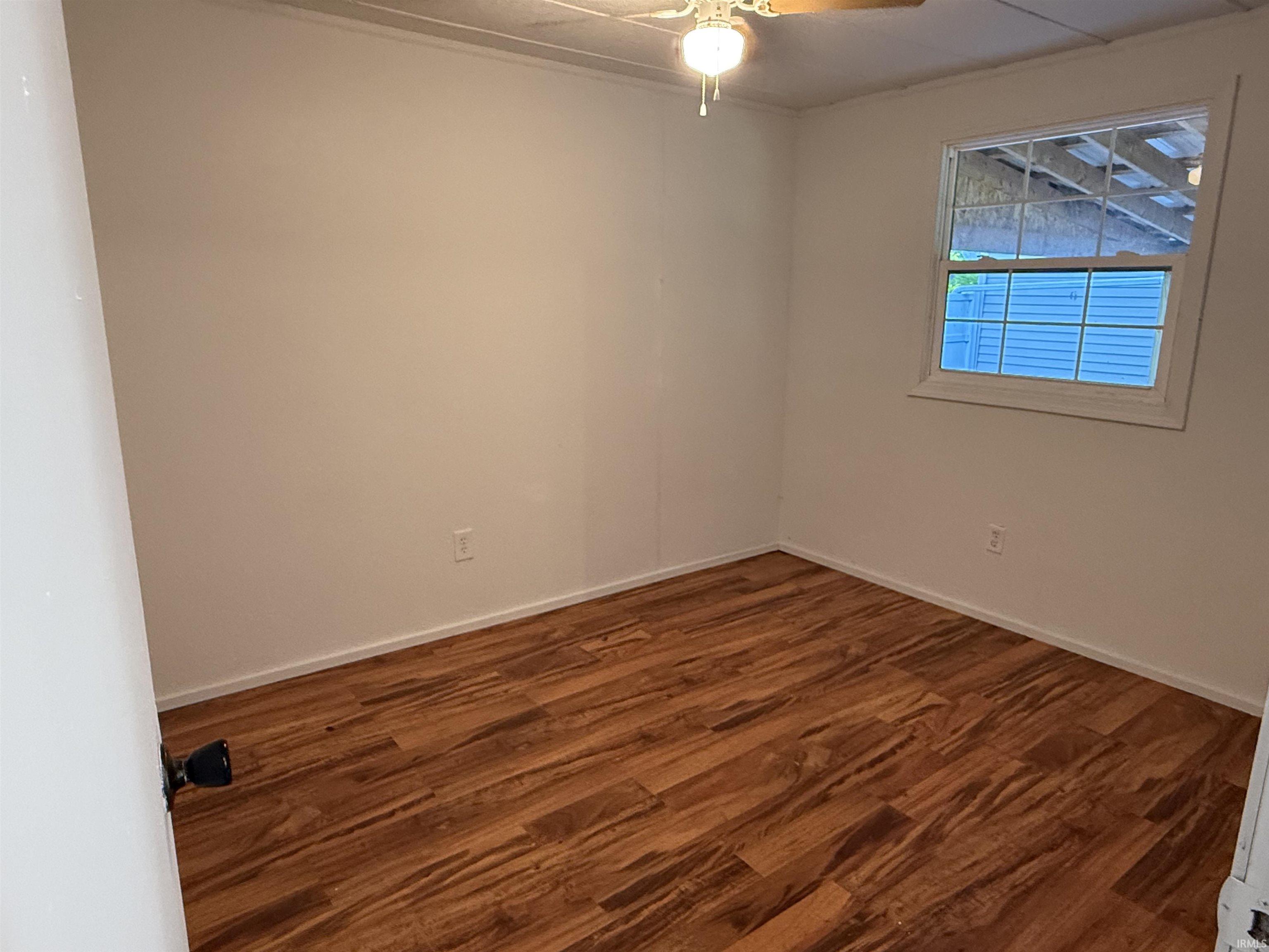 Room featuring wood-finish flooring, white walls, and a multi-pane window