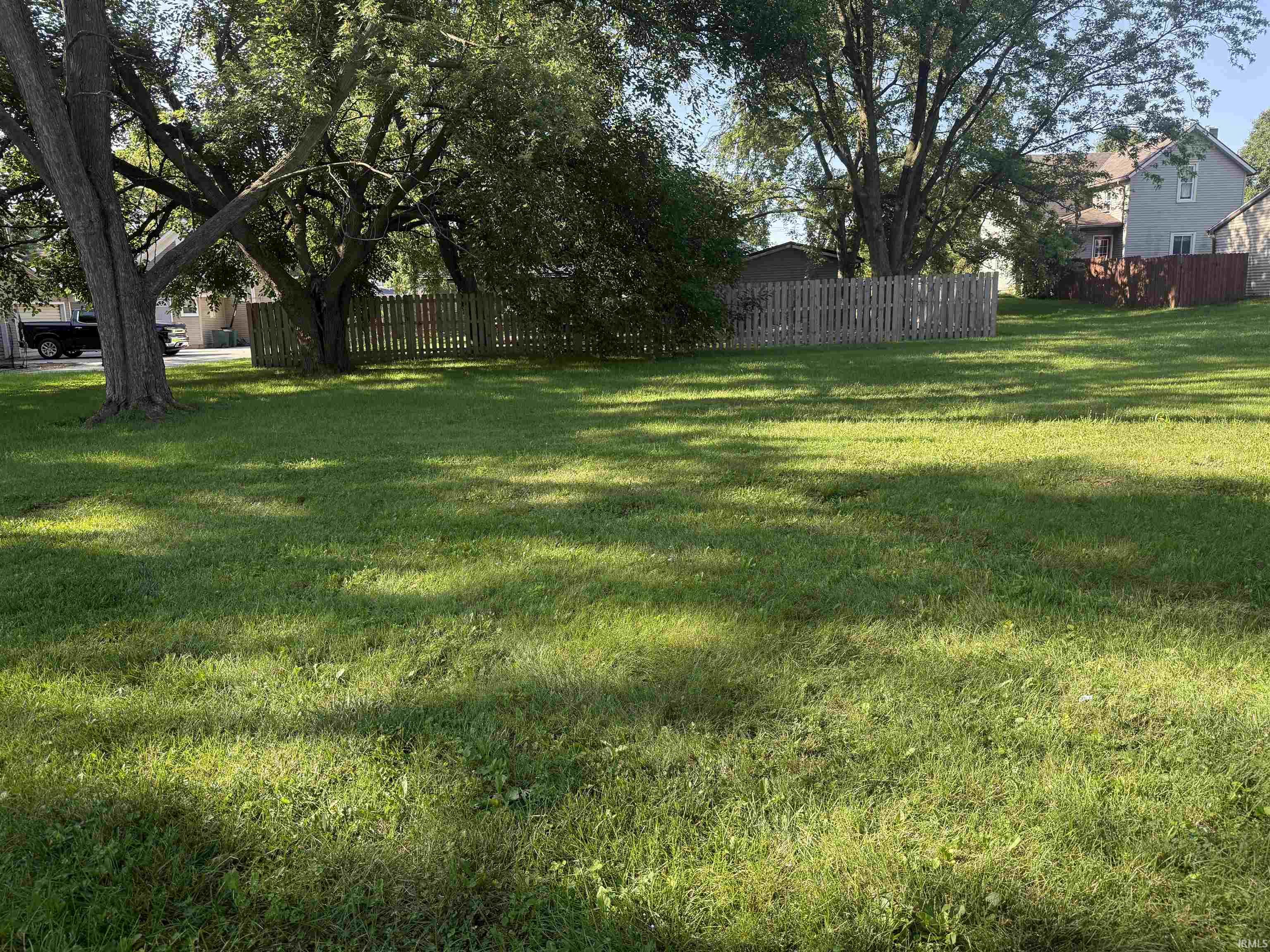 Expansive outdoor space featuring a lush green lawn and mature trees