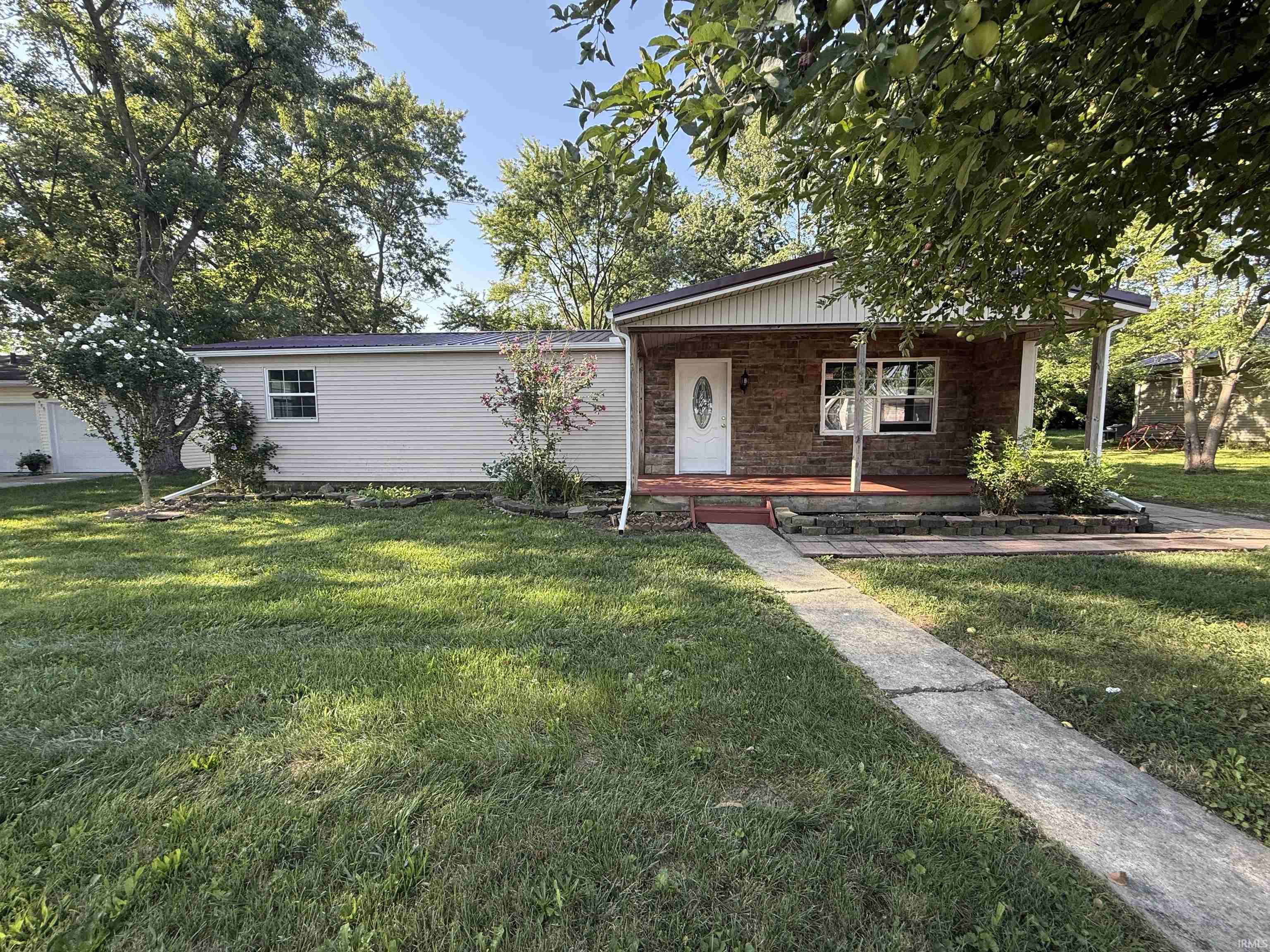 Ranch-style residence featuring a stone and siding exterior, covered front porch, and a concrete pathway leading to the entrance
