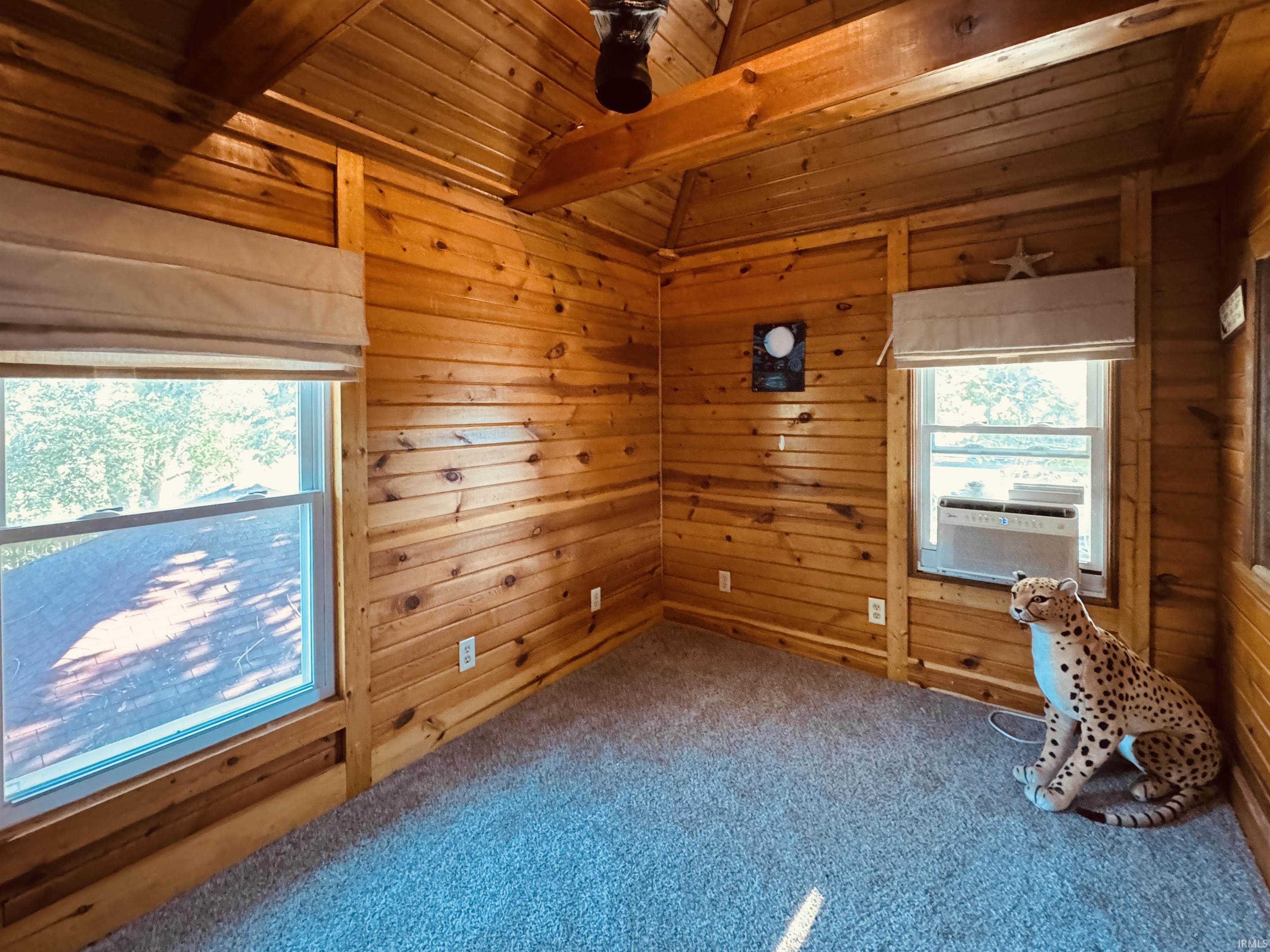 Wood-paneled interior featuring vaulted ceilings and light gray carpeting
