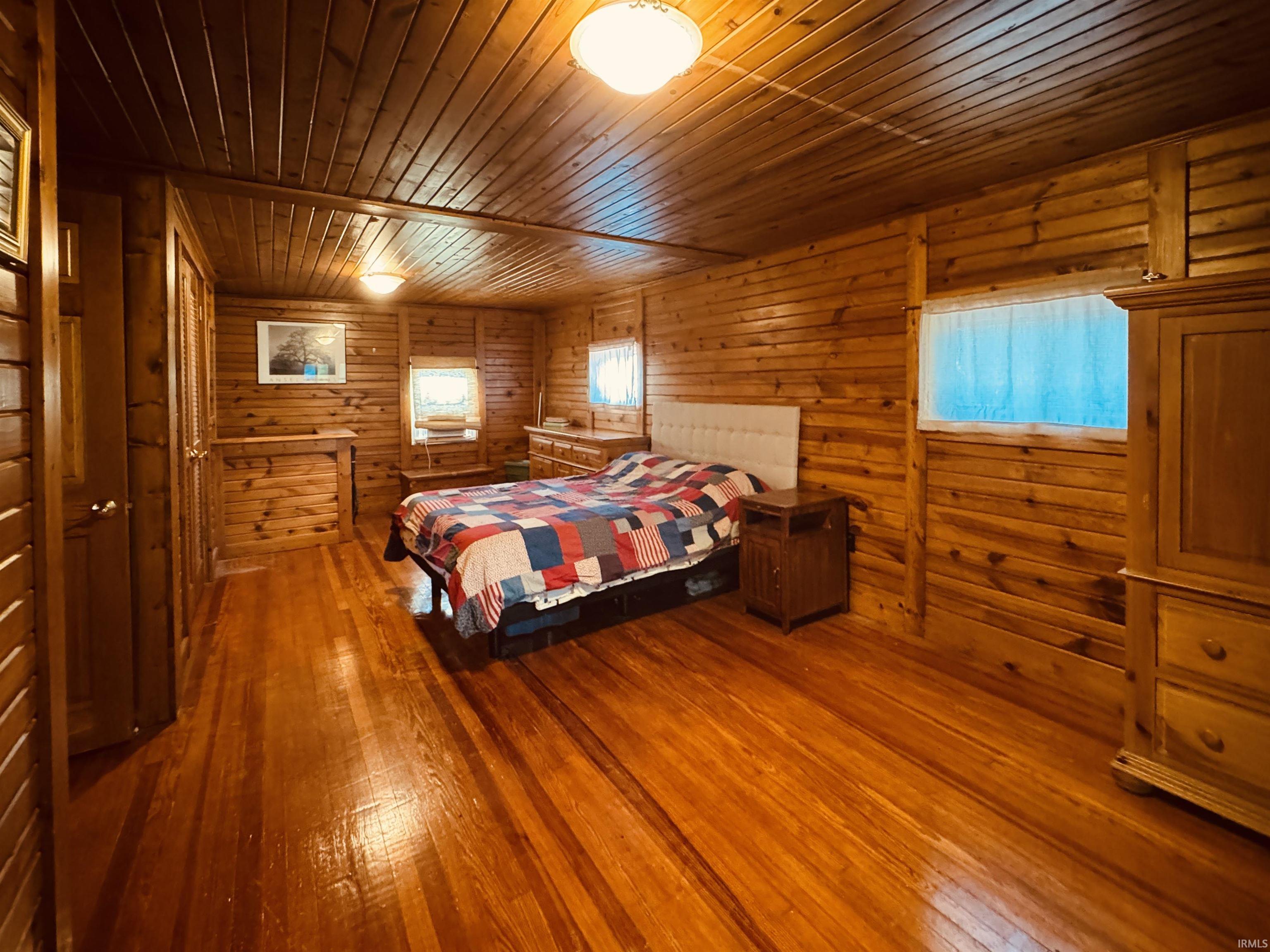 Spacious room featuring wood-finish flooring, wood-paneled walls, and a wood-paneled ceiling