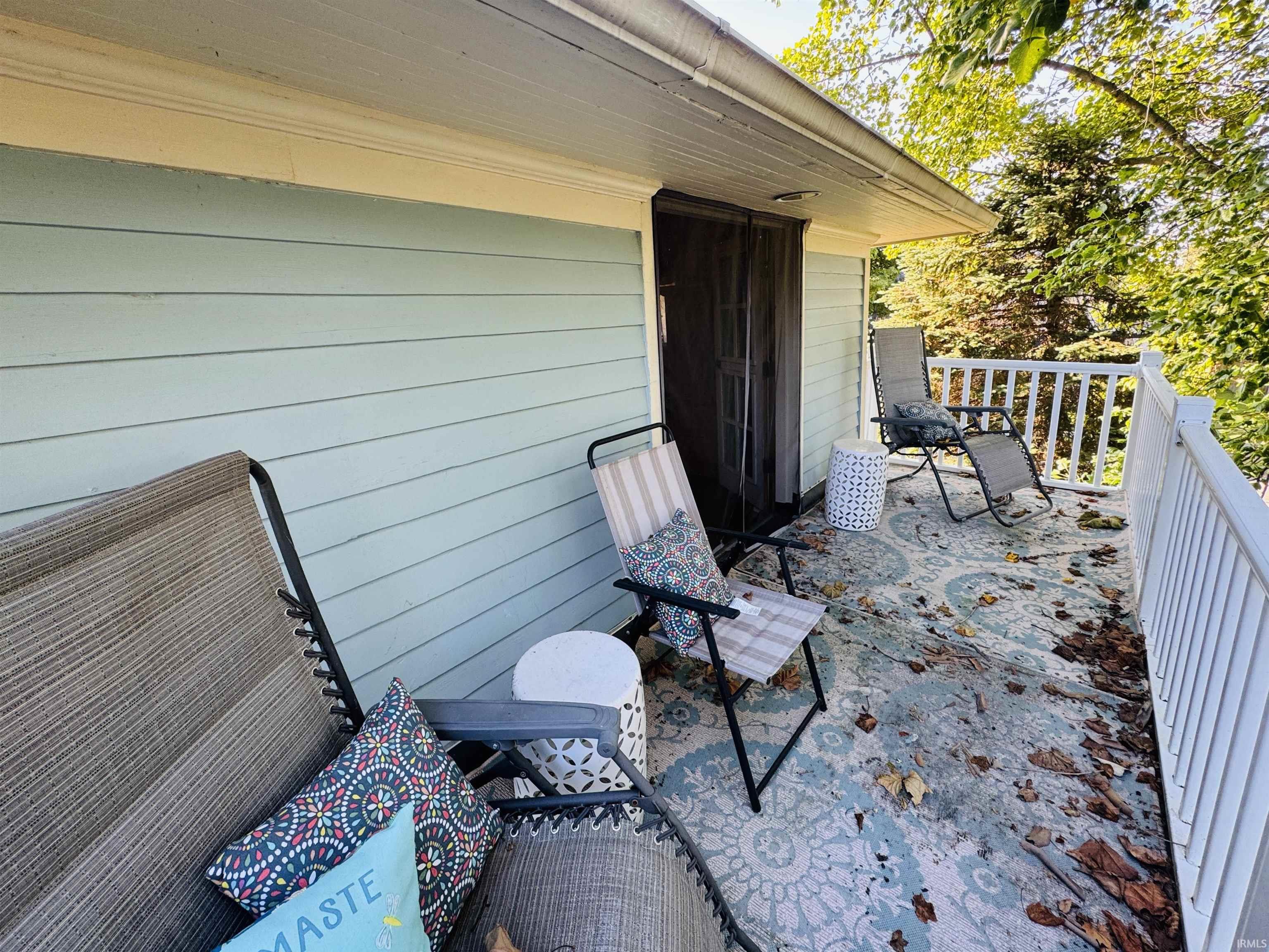 Outdoor deck featuring light blue siding, white railing, and a dark screened door